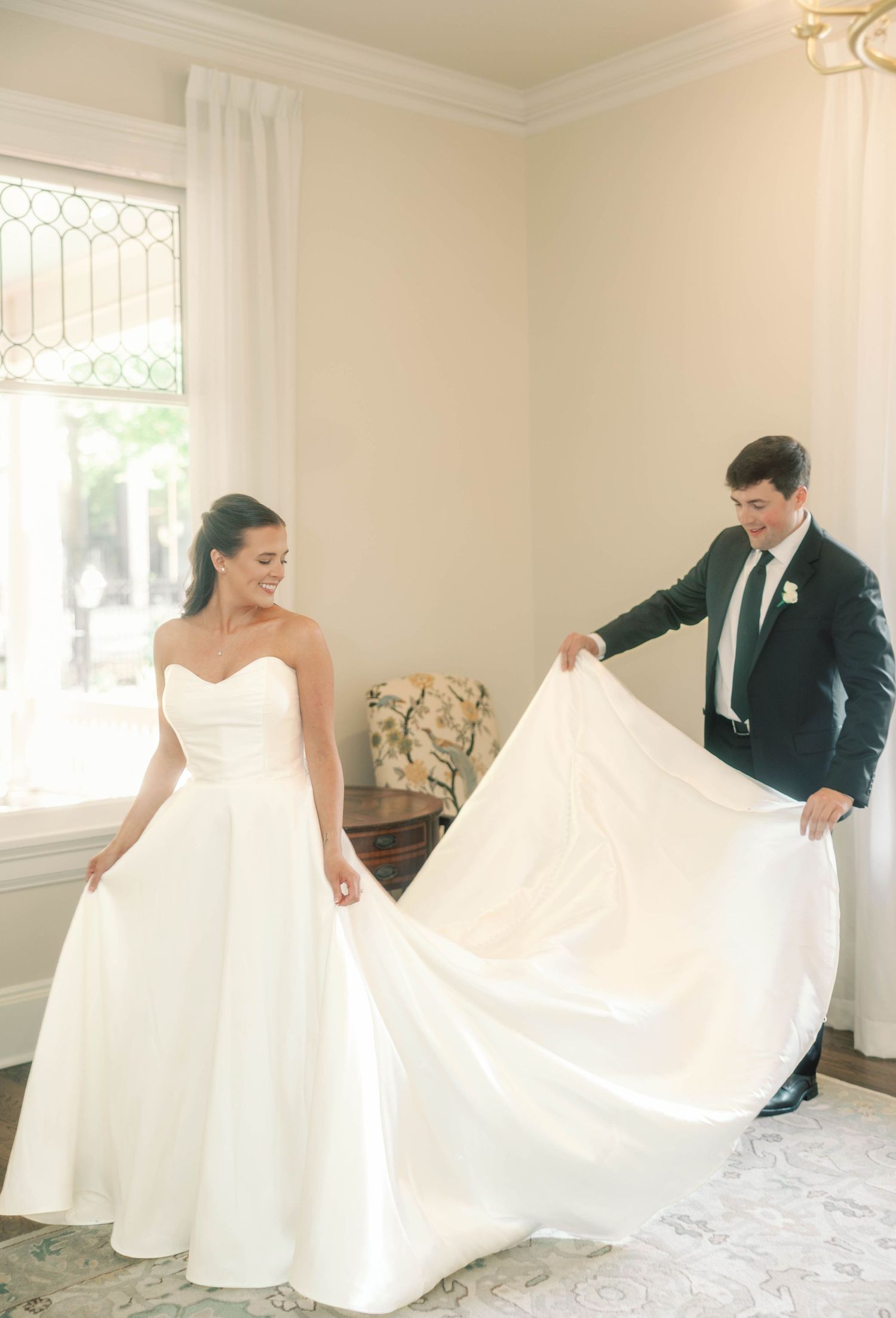 An elegant white wedding gown being displayed in a bright room with natural lighting.