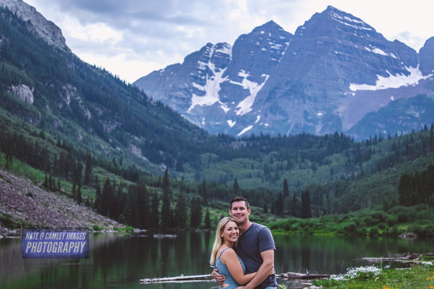 Scenic mountain landscape with snow-capped peaks reflected in a tranquil alpine lake surrounded by evergreen forest.
