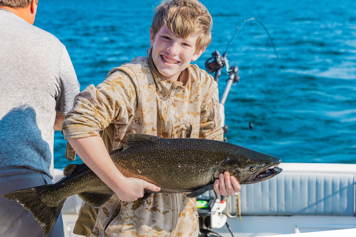 A group of anglers display their freshly caught lake trout while fishing on bright blue waters.