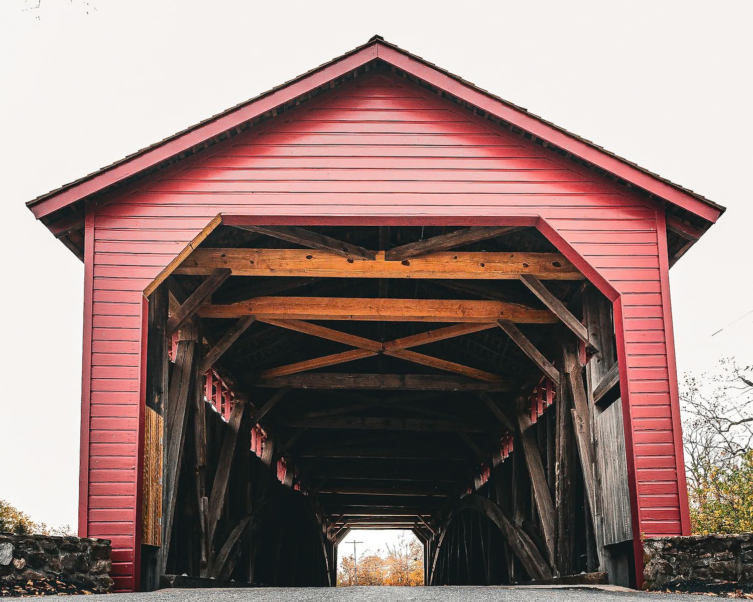 Panoramic view of a red covered bridge with wooden beam construction and rustic architecture.