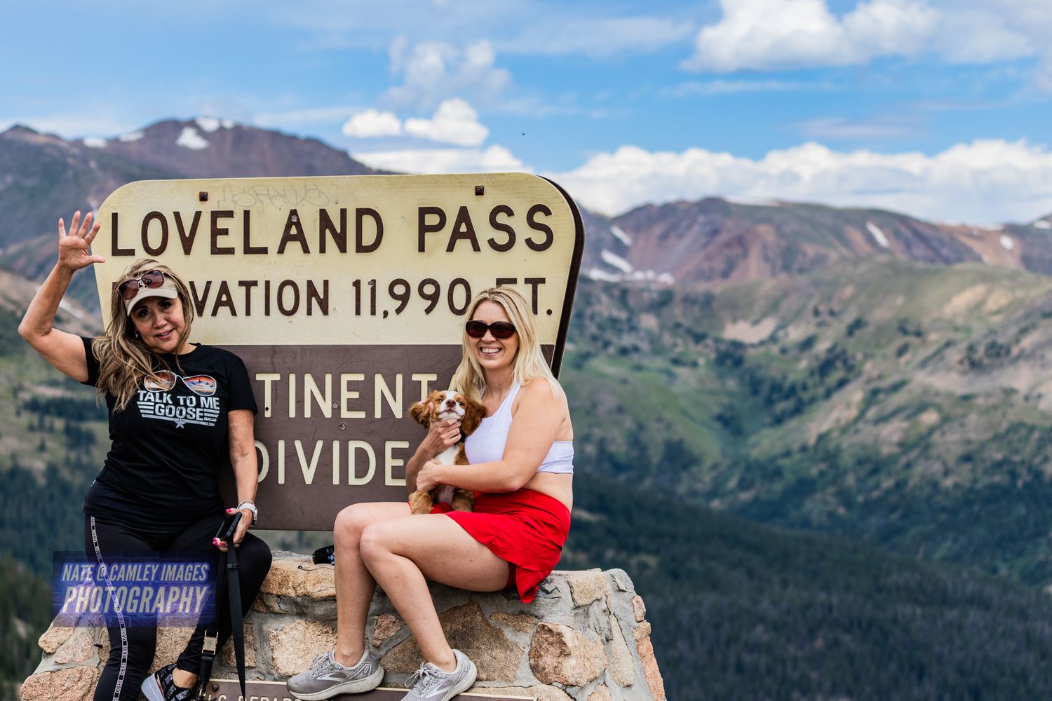 People enjoying scenic mountain views at Loveland Pass Continental Divide sign in Colorado's Rocky Mountains.