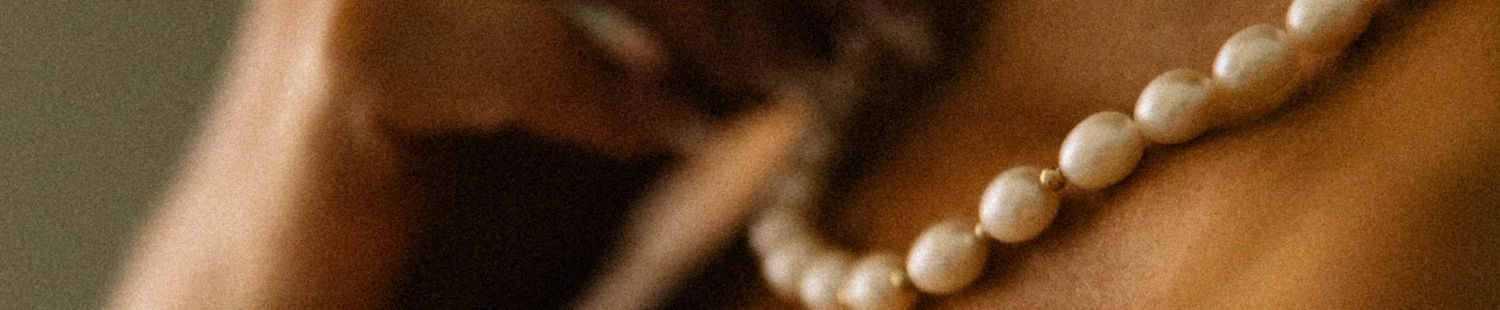 Close-up of a person wearing an elegant white pearl necklace against warm skin tones.