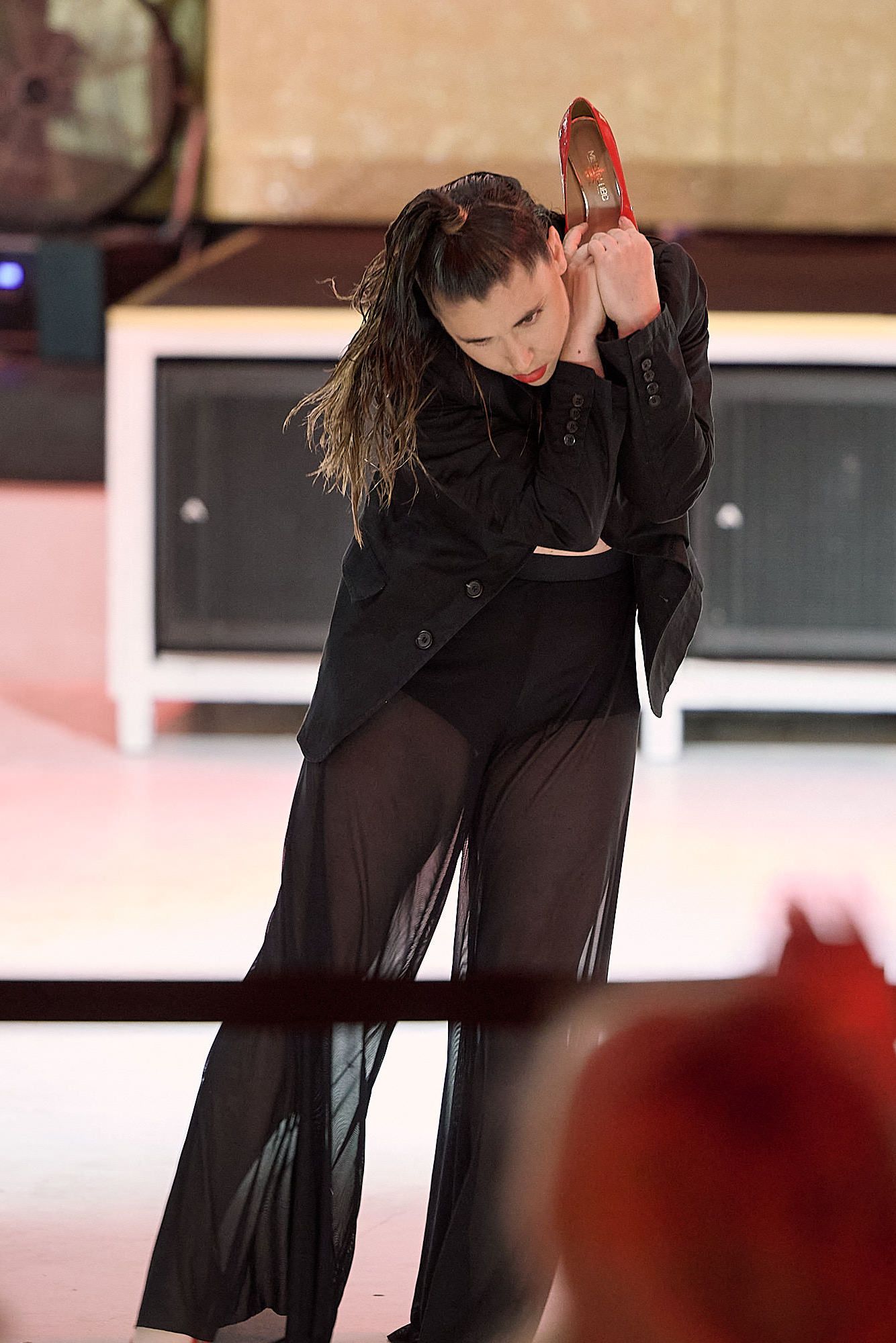 Figure skater performs graceful movement on ice while wearing a flowing black costume at performance event.