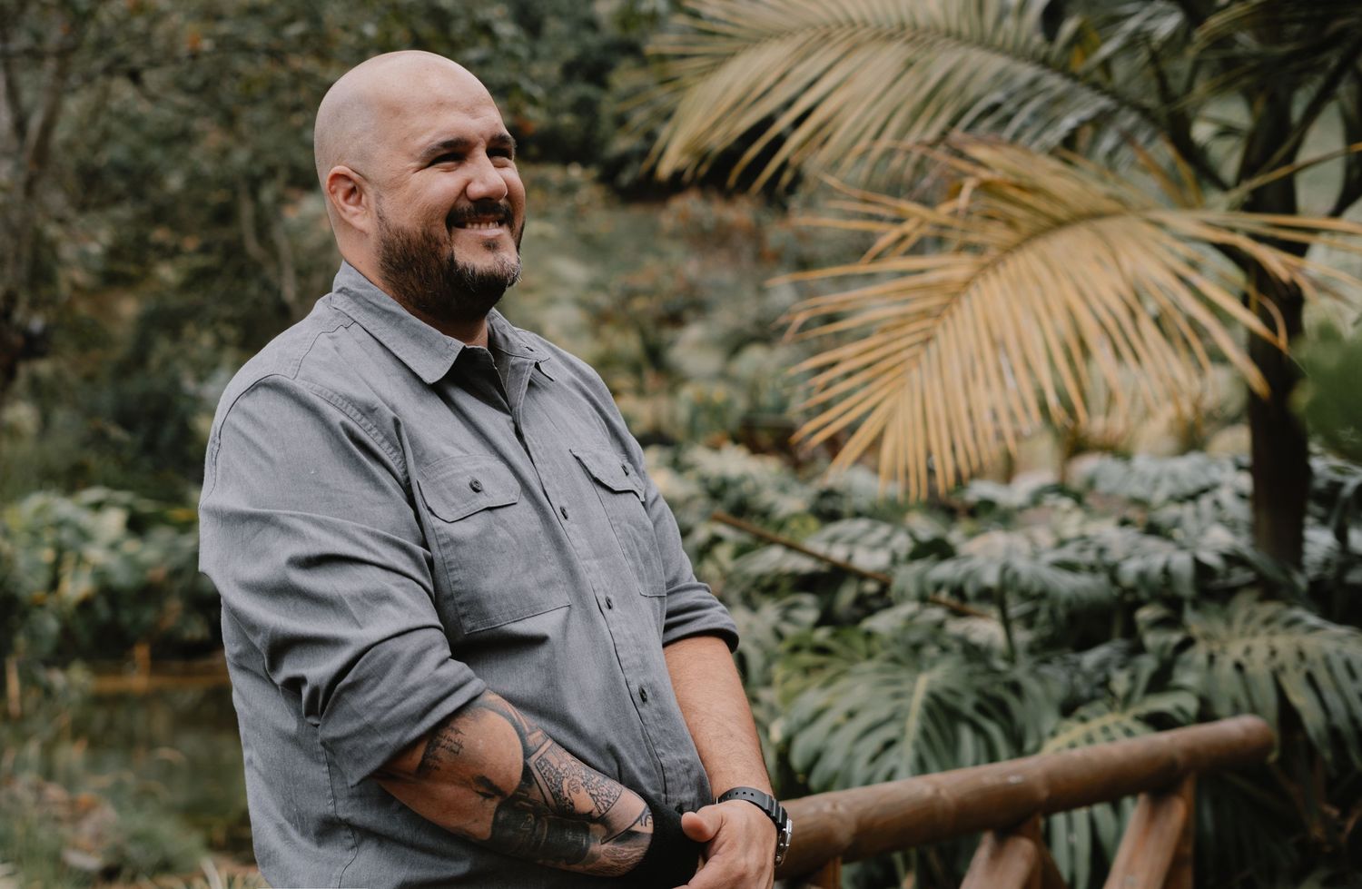 A person wearing a gray sweater poses in multiple casual shots against a lush green outdoor backdrop with palm fronds.