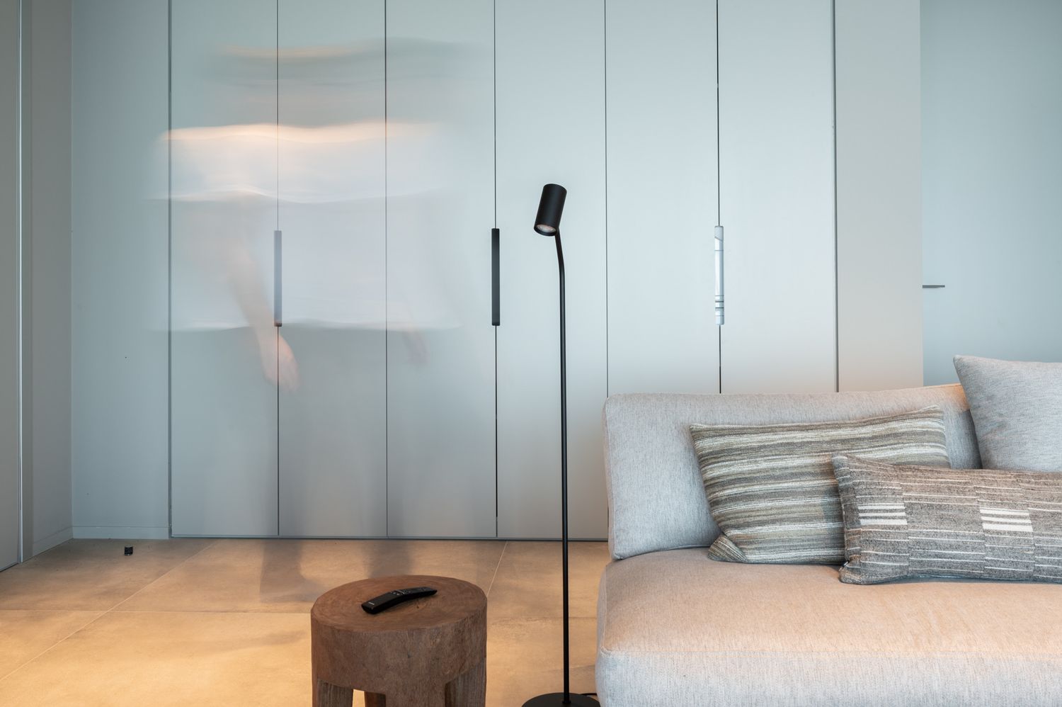 Minimalist bedroom interior with light blue walls and built-in storage.