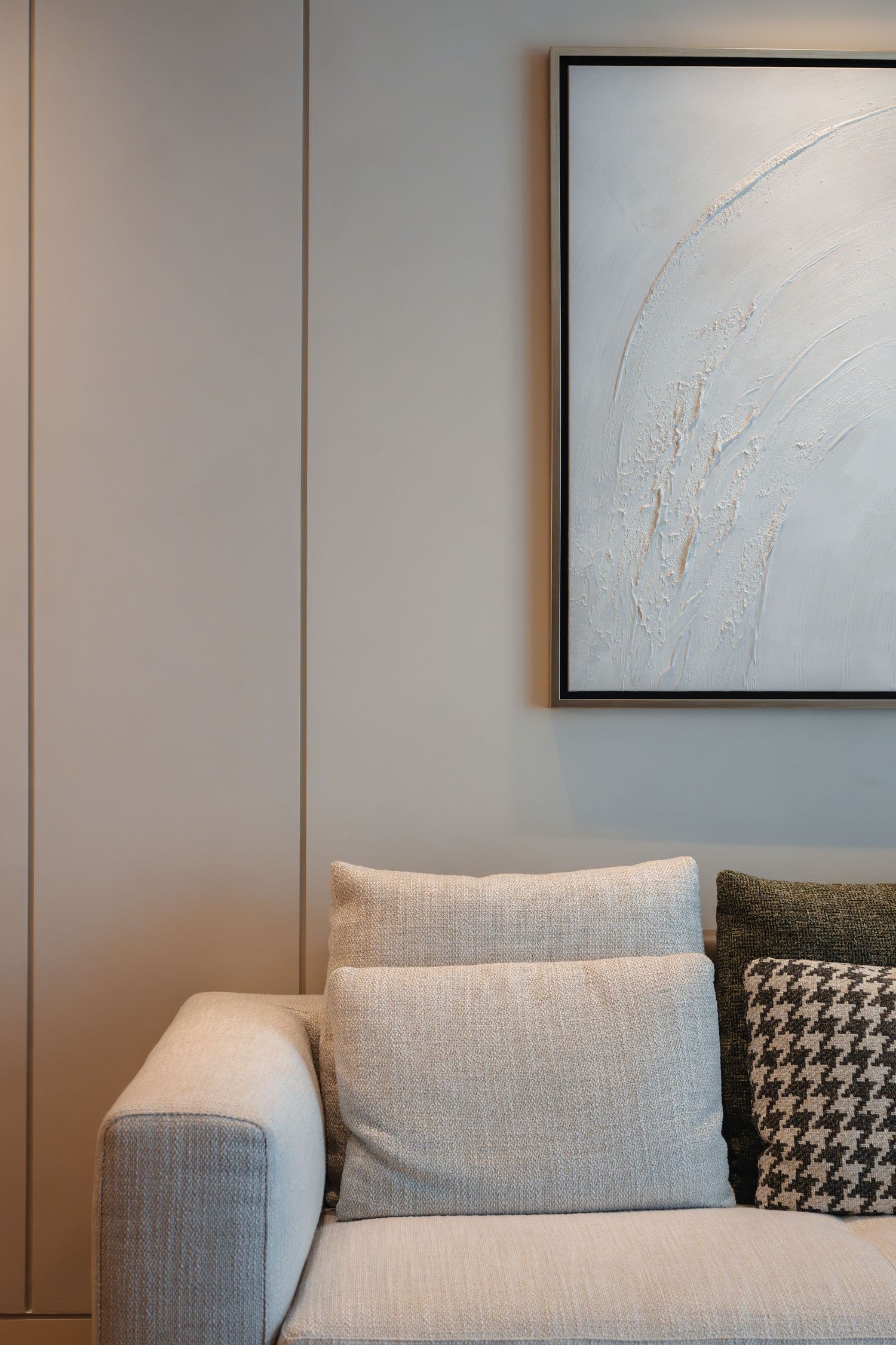 Modern living room interior with gray upholstered couch and minimalist framed artwork on neutral walls, Dubai, by Parallel Studios