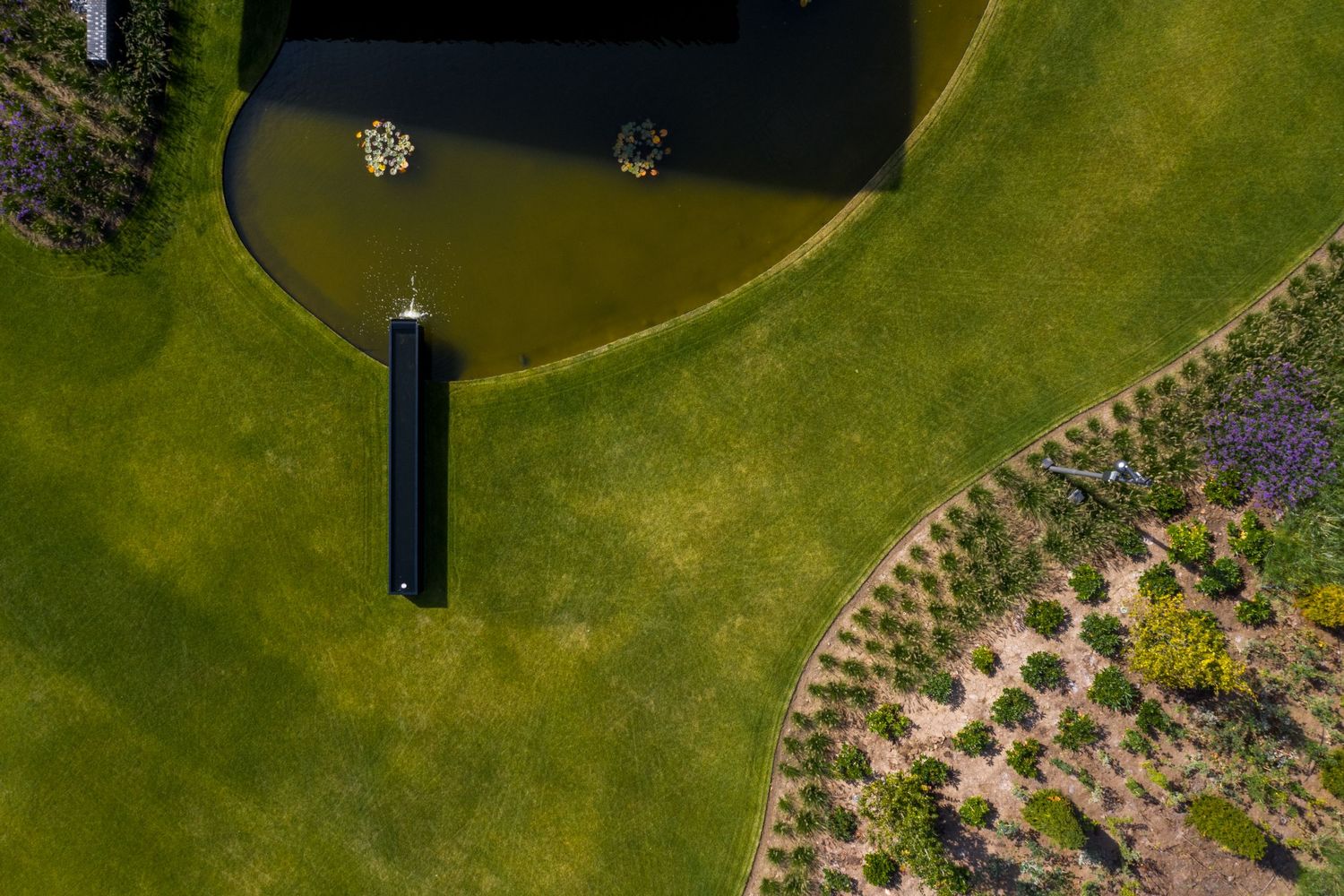 Aerial shot of landscaped garden with circular water feature and geometric planting patterns, by Parallel Studios