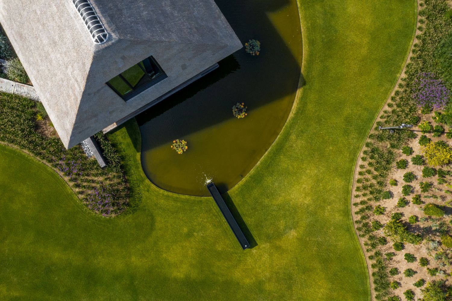 Aerial view of a modern building with green landscaping and curved architectural features, by Parallel Studios
