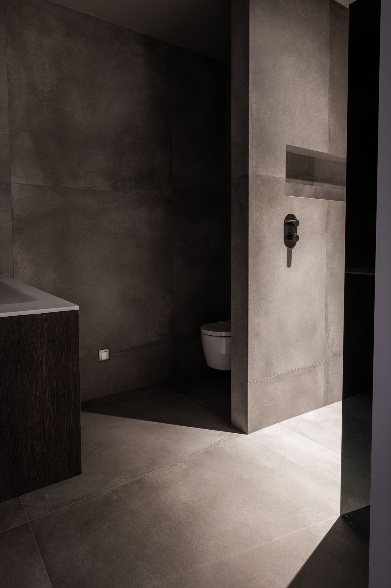 Minimalist concrete hallway with dramatic lighting and angular shadows.
