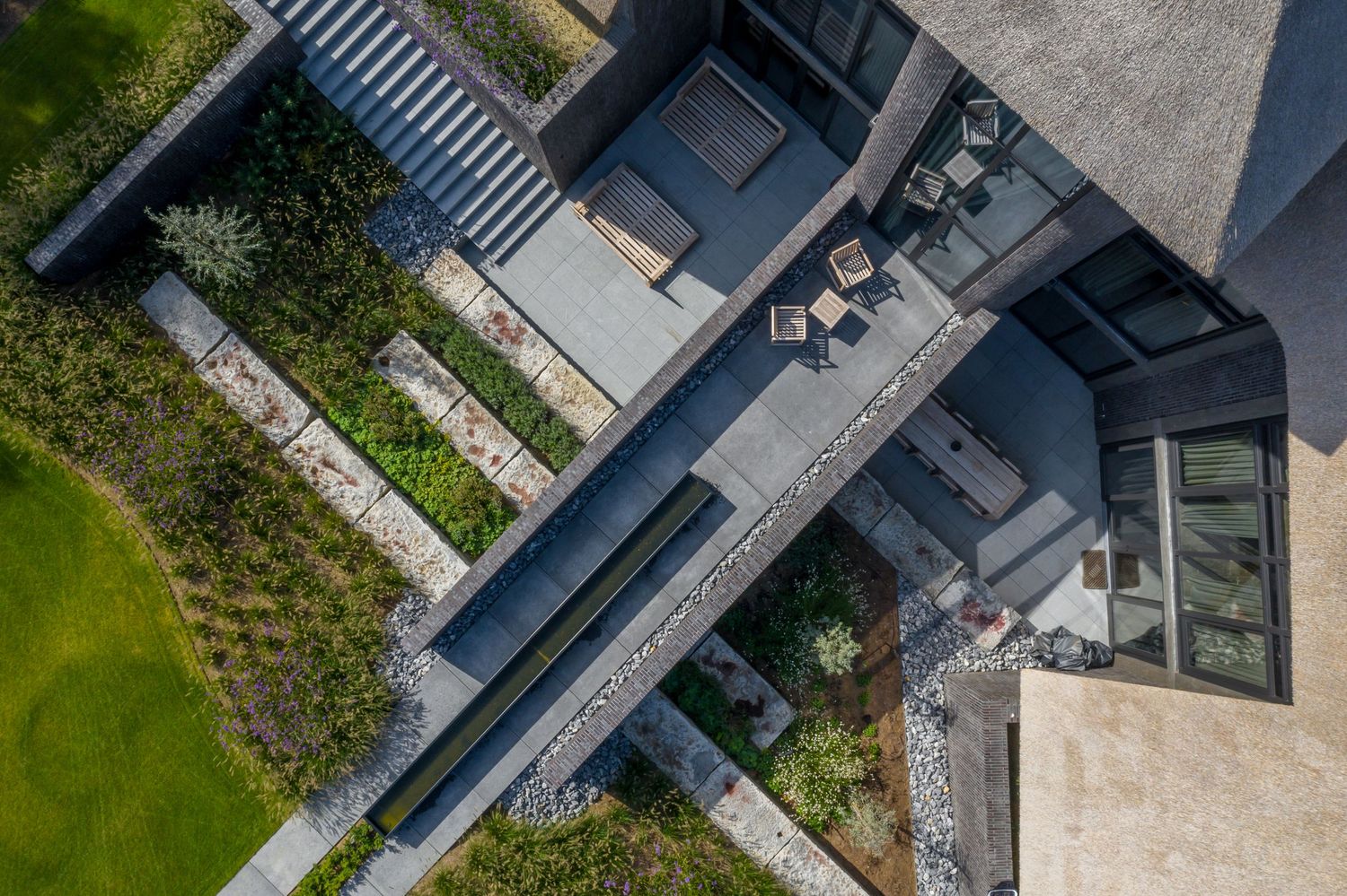 Birds-eye view of a contemporary deck with outdoor seating and geometric garden pathways, by Parallel Studios