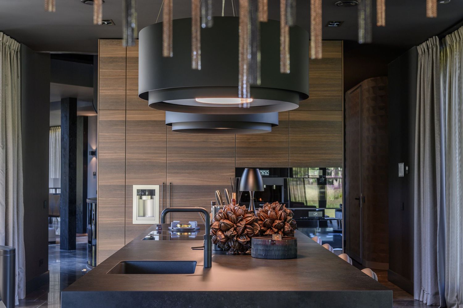 Contemporary open-plan living space with wood paneling and suspended lighting fixtures.