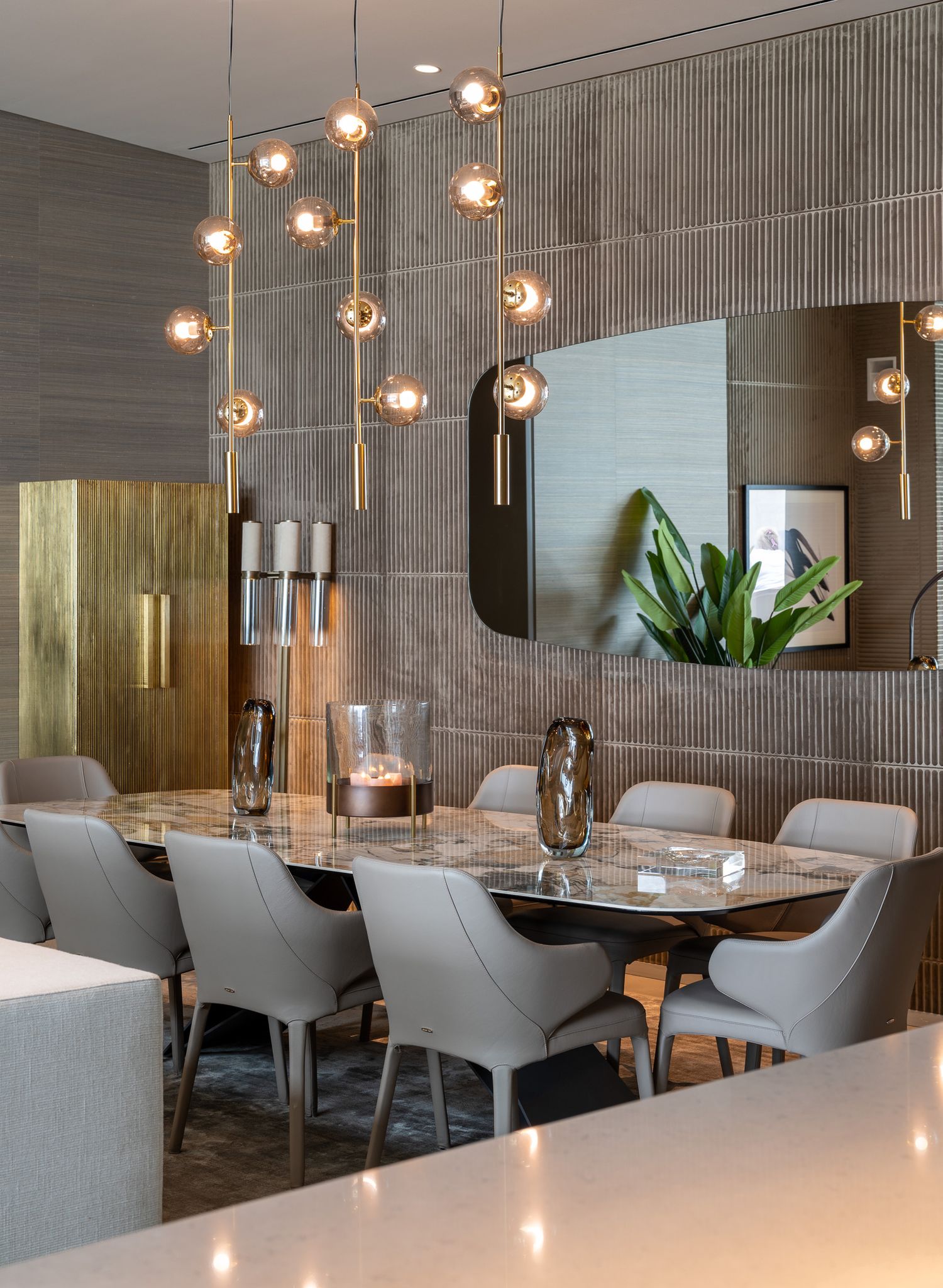 Modern dining space with hanging glass pendant lights, grey upholstered chairs, and textured wall panels, Algarve, by Parallel Studios
