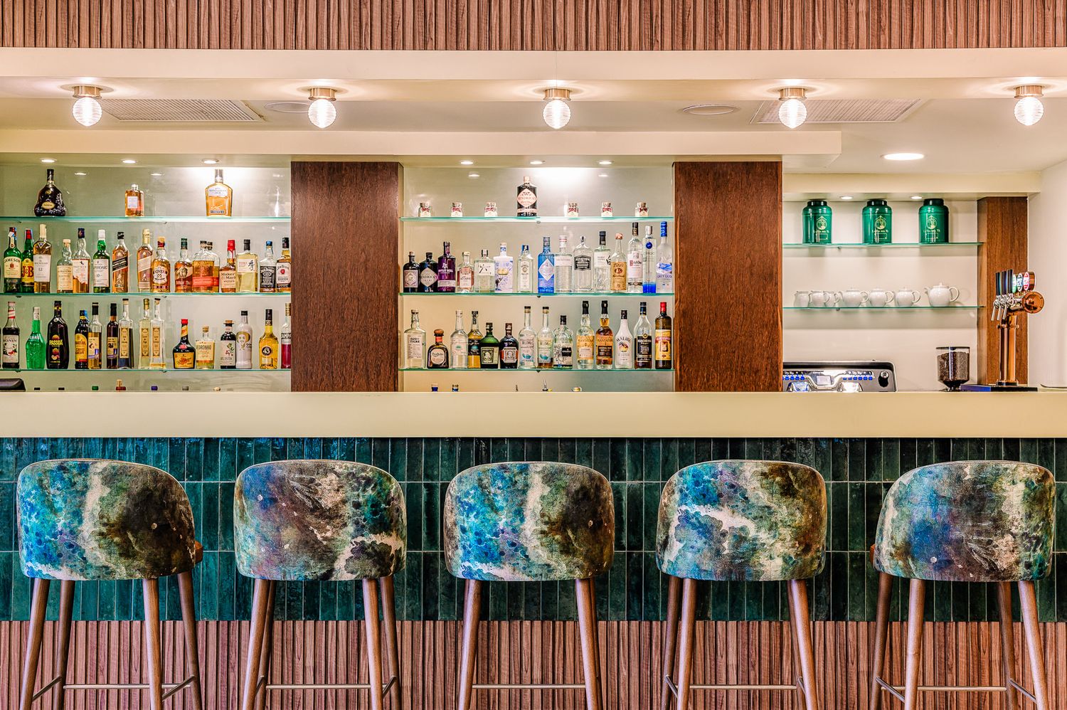 Modern Hotel bar counter with extensive liquor display and wood accents in upscale setting in the Algarve, by Parallel Studios