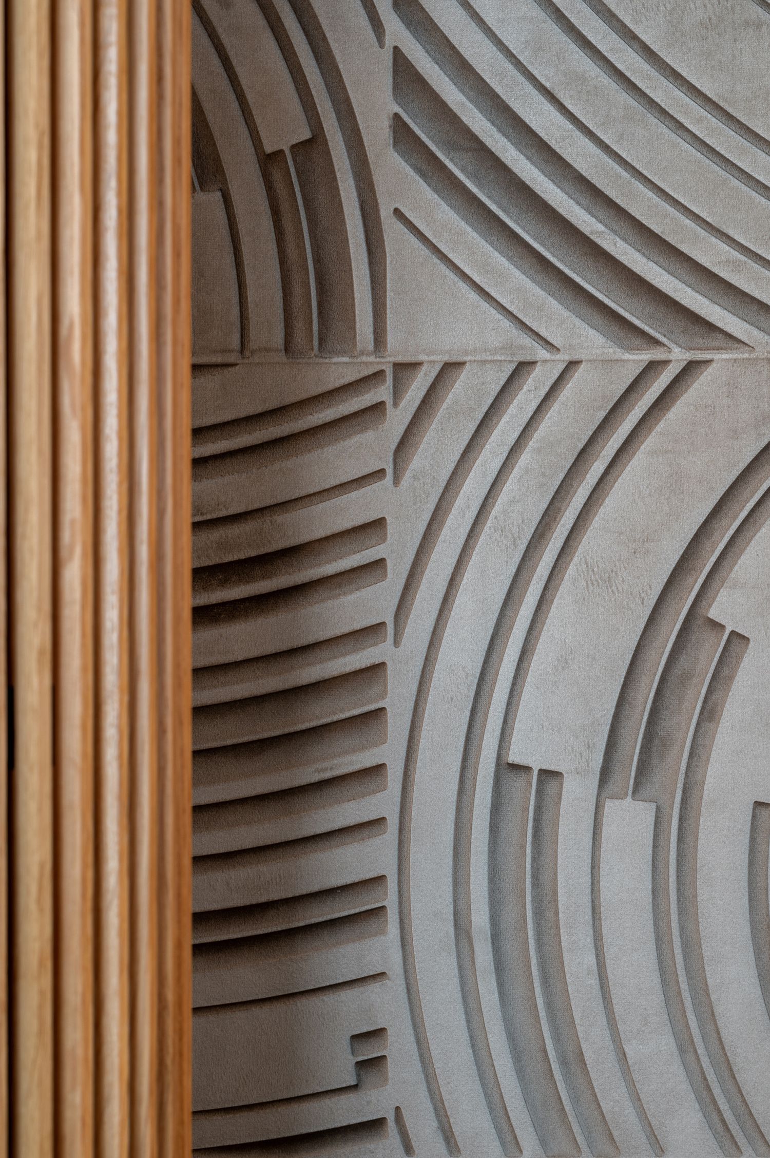 Abstract architectural wall detail showing curved geometric patterns with wooden pillar accents.
