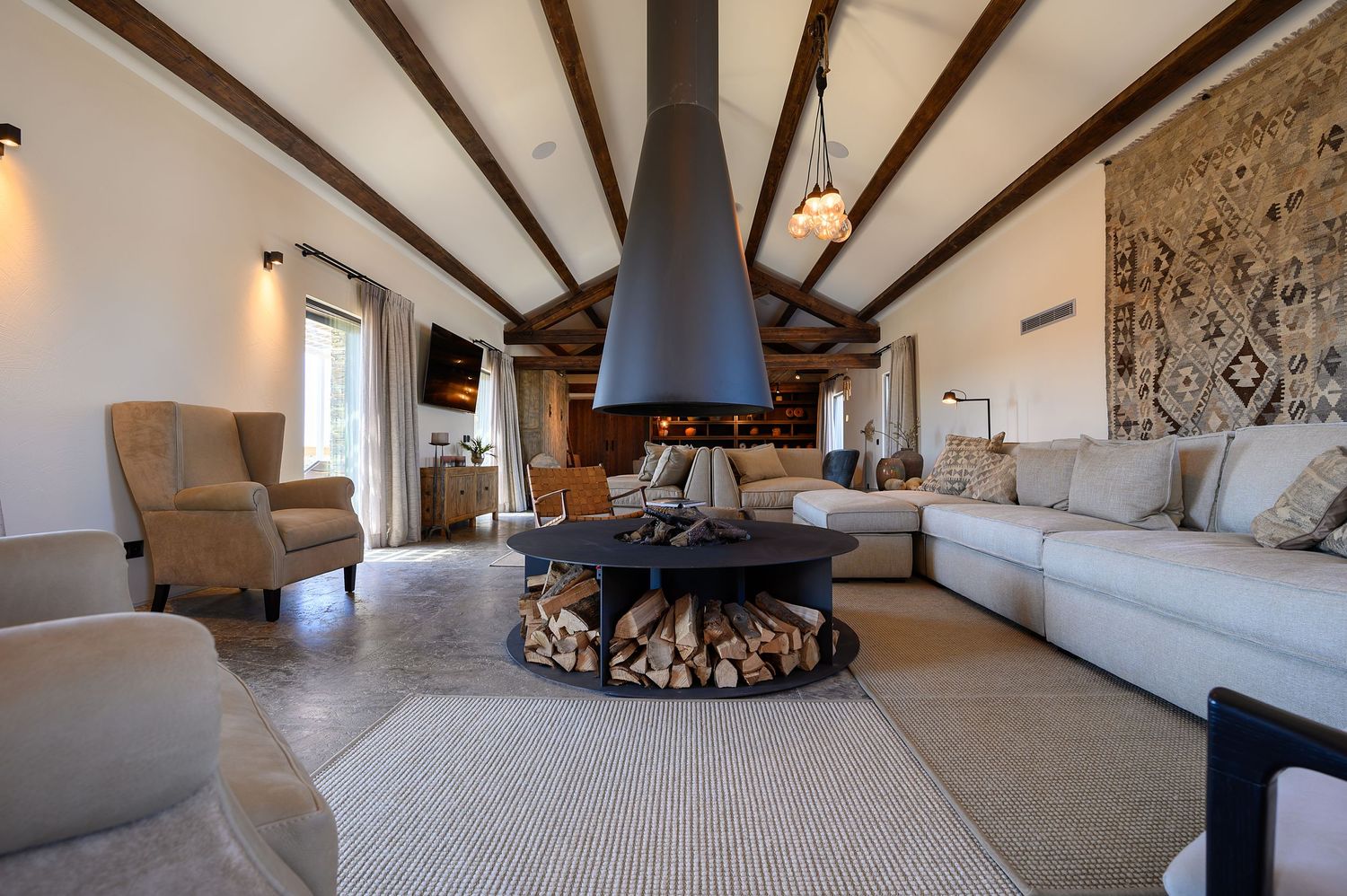 Living room with exposed wooden beams and modern fireplace featuring comfortable seating in the Algarve, by Parallel Studios