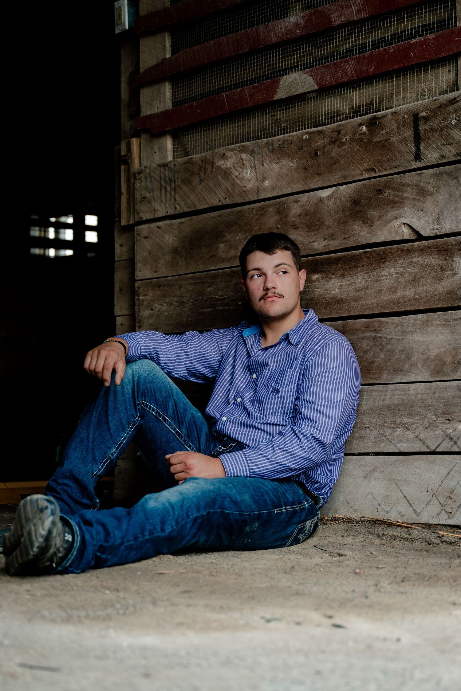 A series of senior portrait photos showing someone reclining on a wooden floor in a blue striped shirt and jeans.