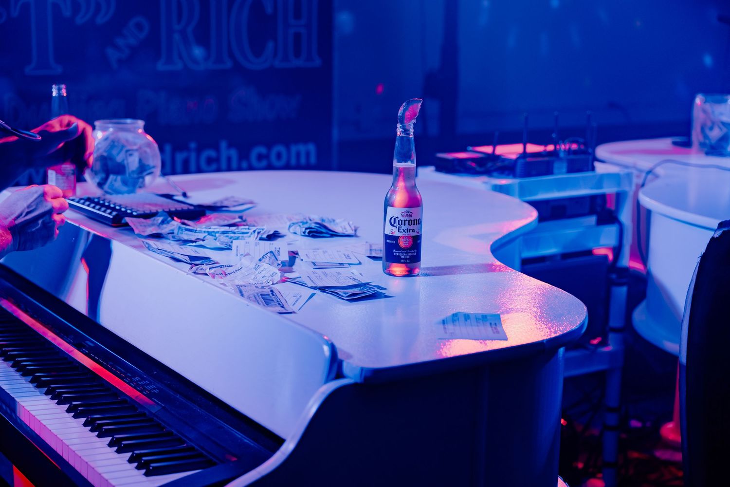 A series of dimly lit workstations with computer monitors and keyboards bathed in blue and purple lighting.