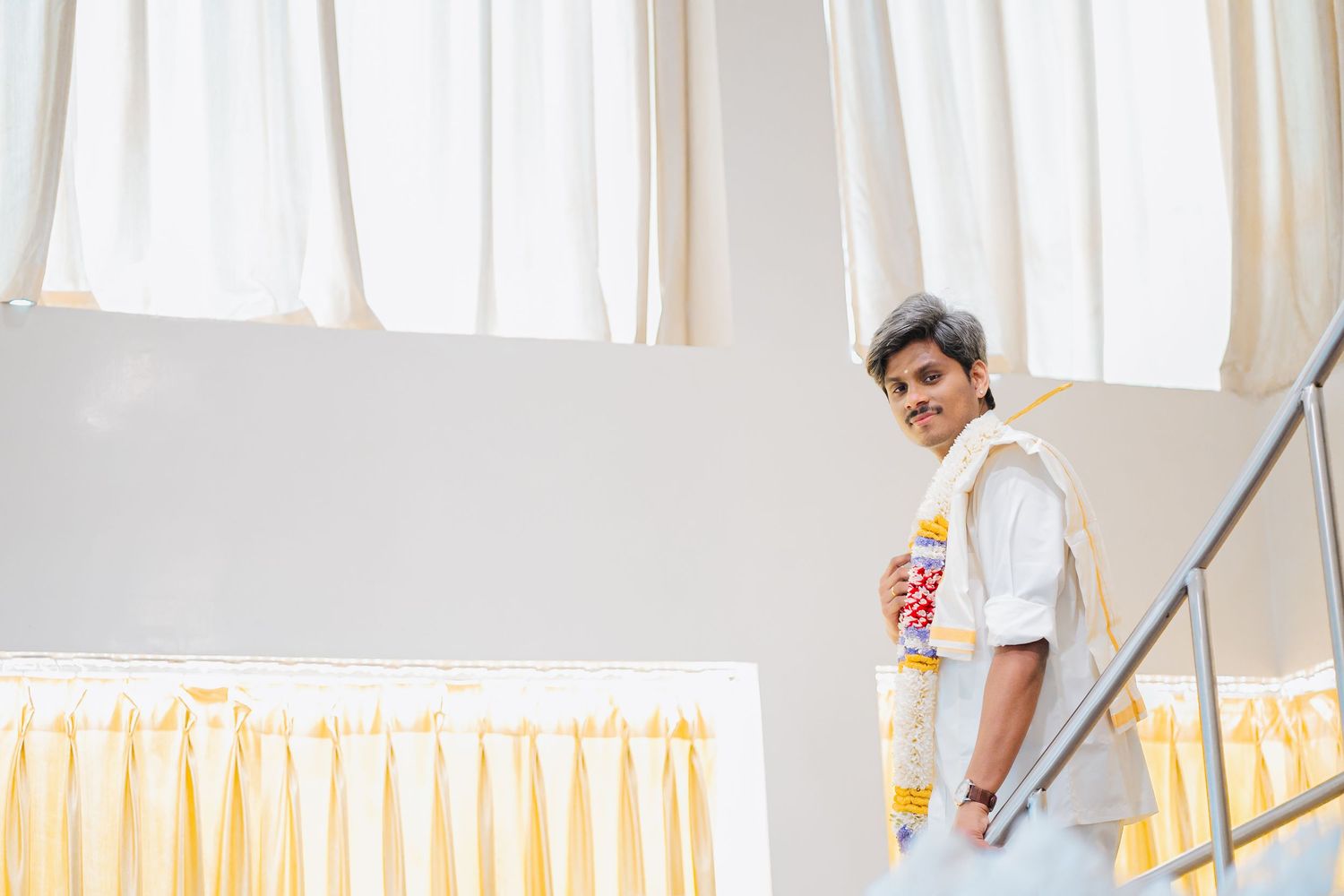 Person standing on stairs near white curtains and decor in clean bright setting.