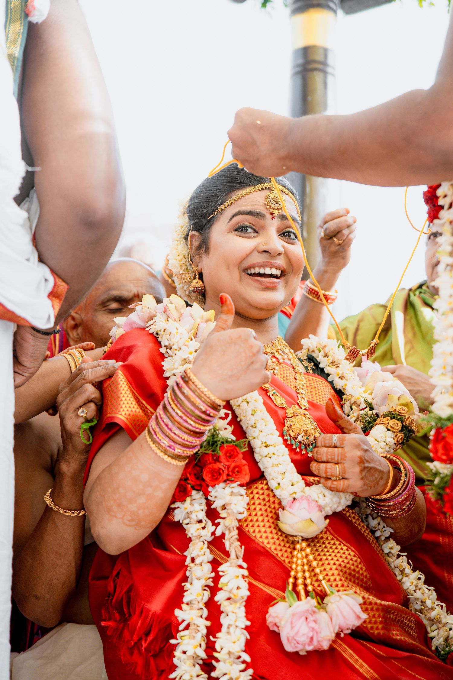 Joyful traditional wedding ceremony with bride wearing red silk saree and floral garlands.