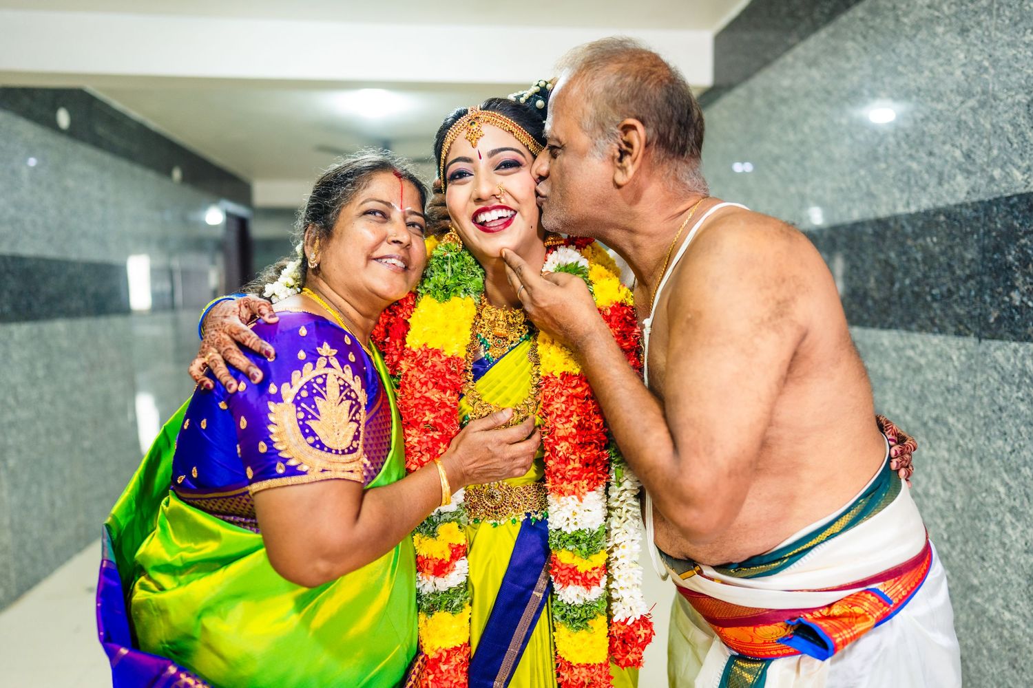 Colorful celebration with traditional South Indian attire and floral garlands during a family ceremony.