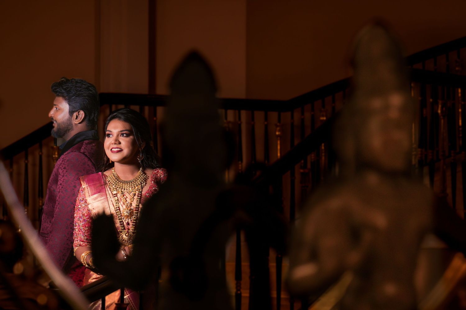 Couple sharing joyful moment on wooden staircase during traditional wedding celebration.