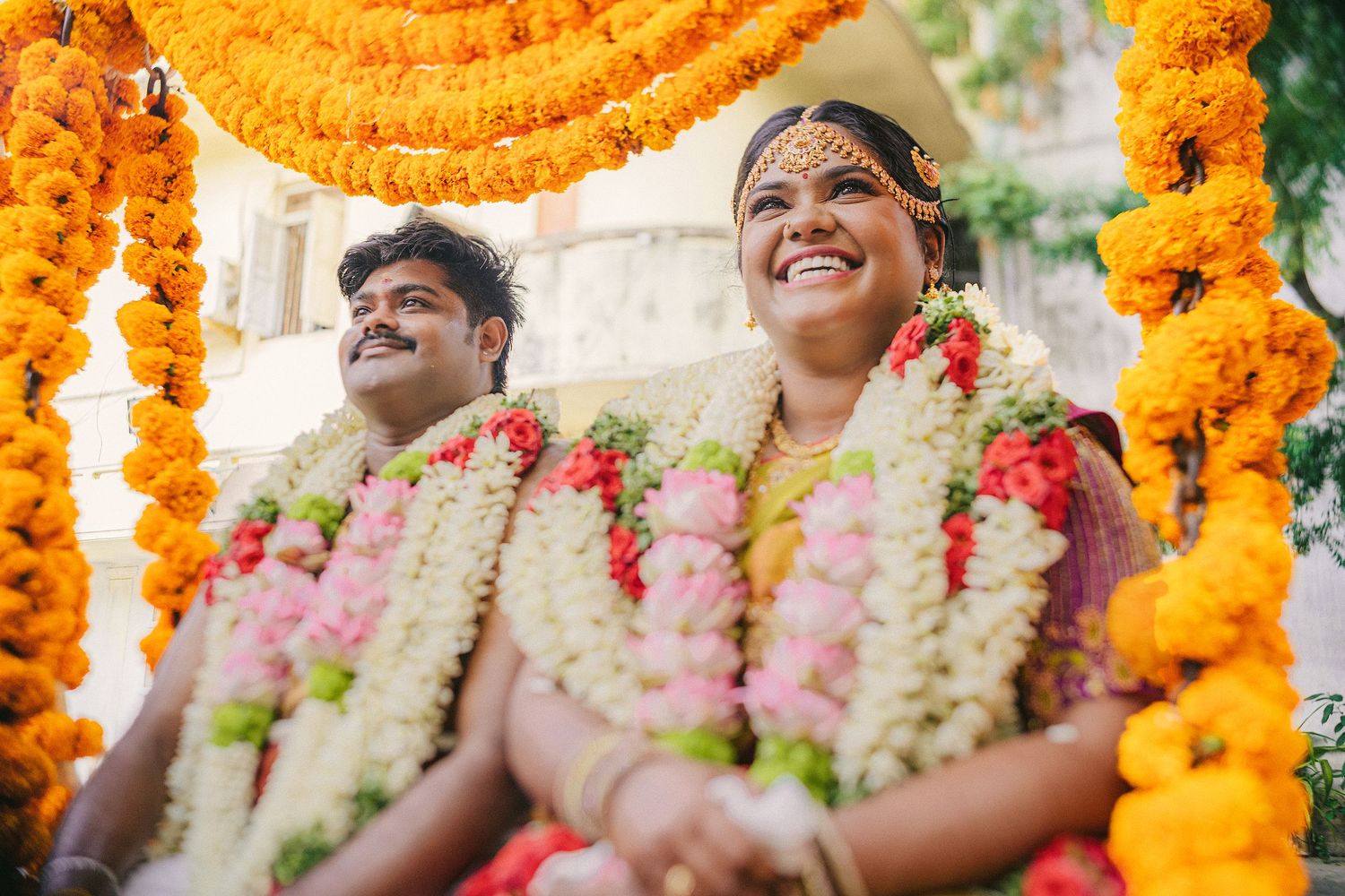 Traditional South Indian wedding moment captured under beautiful orange and white floral arrangements.