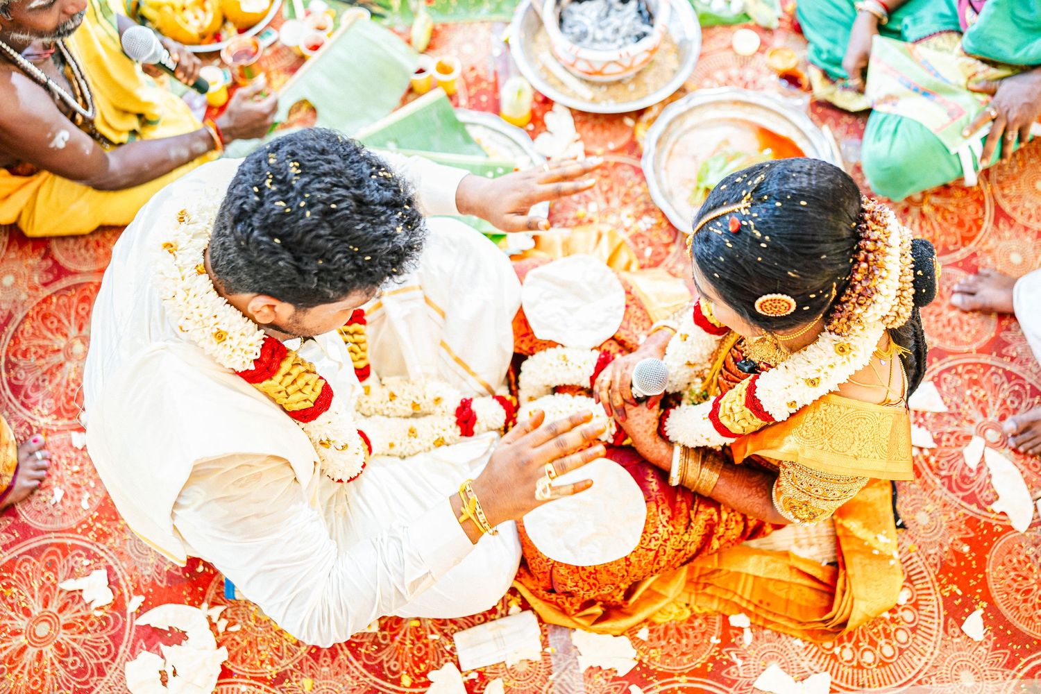 Traditional Indian ceremony with ritual items and decorations on a red patterned cloth.