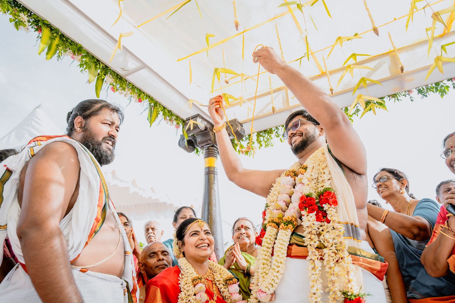 Festive wedding ceremony with celebration under decorated mandap with hanging yellow streamers.
