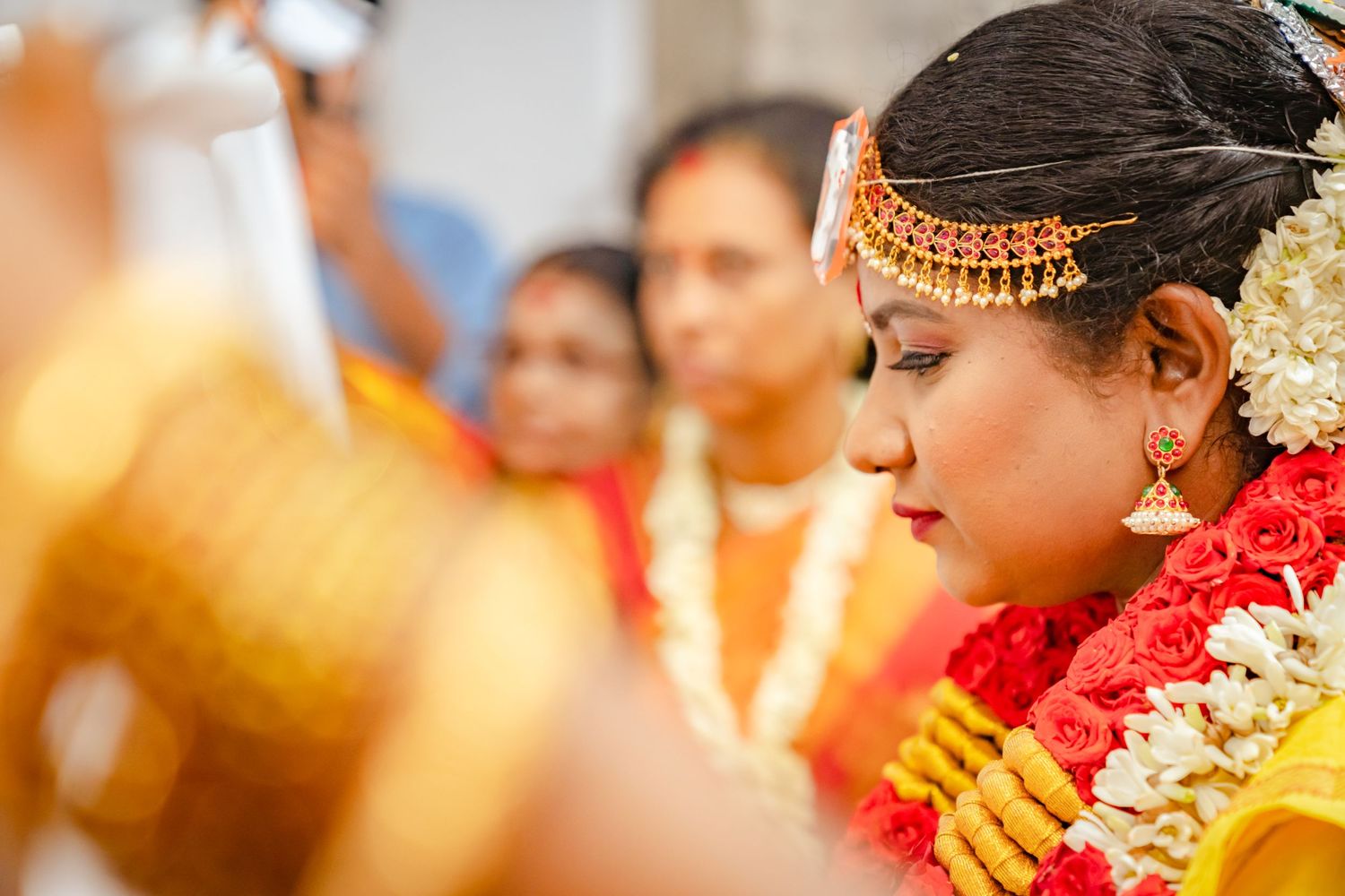 Close-up of intricate bridal jewelry and traditional wedding attire during an Indian ceremony.