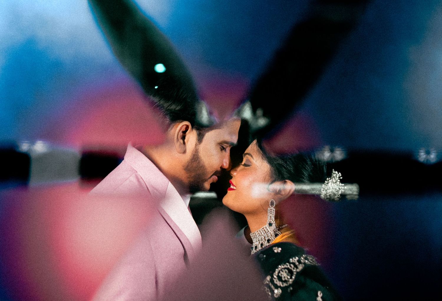 An artistic portrait of two people in formal wear against a dreamy blue background.
