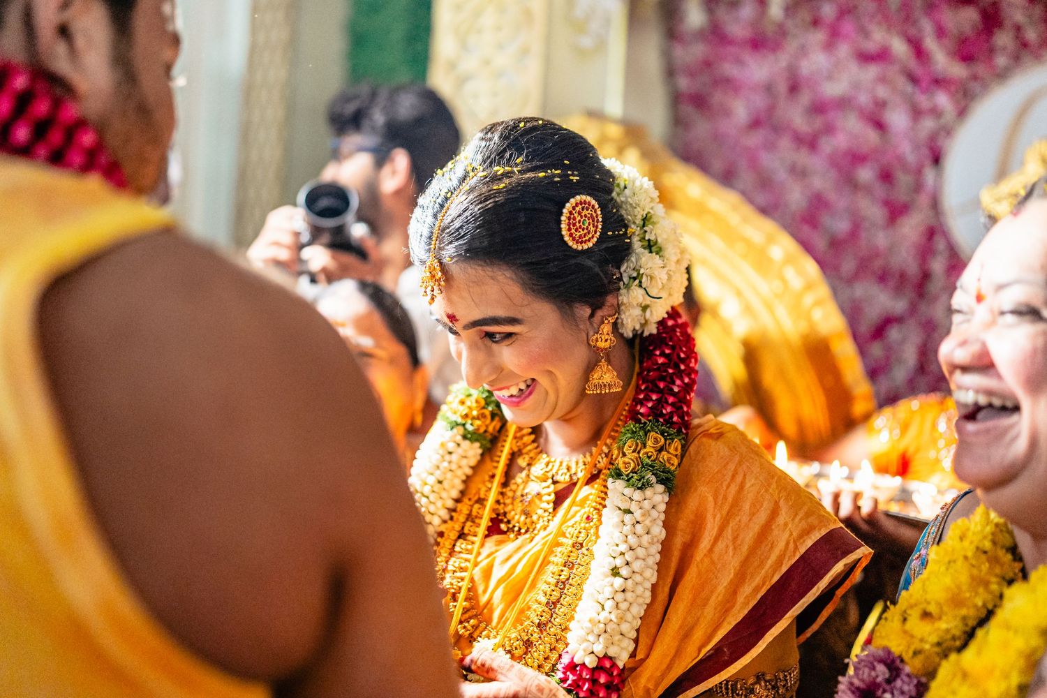 A joyous celebration during a traditional Indian ceremony with people wearing vibrant yellow and orange attire.