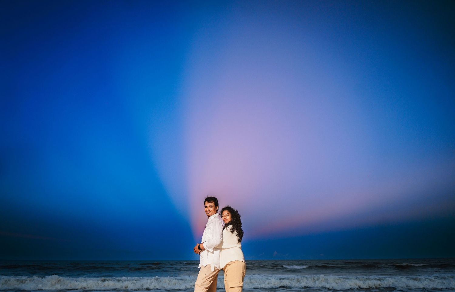 Romantic silhouette against stunning blue and purple sunset sky at the beach.