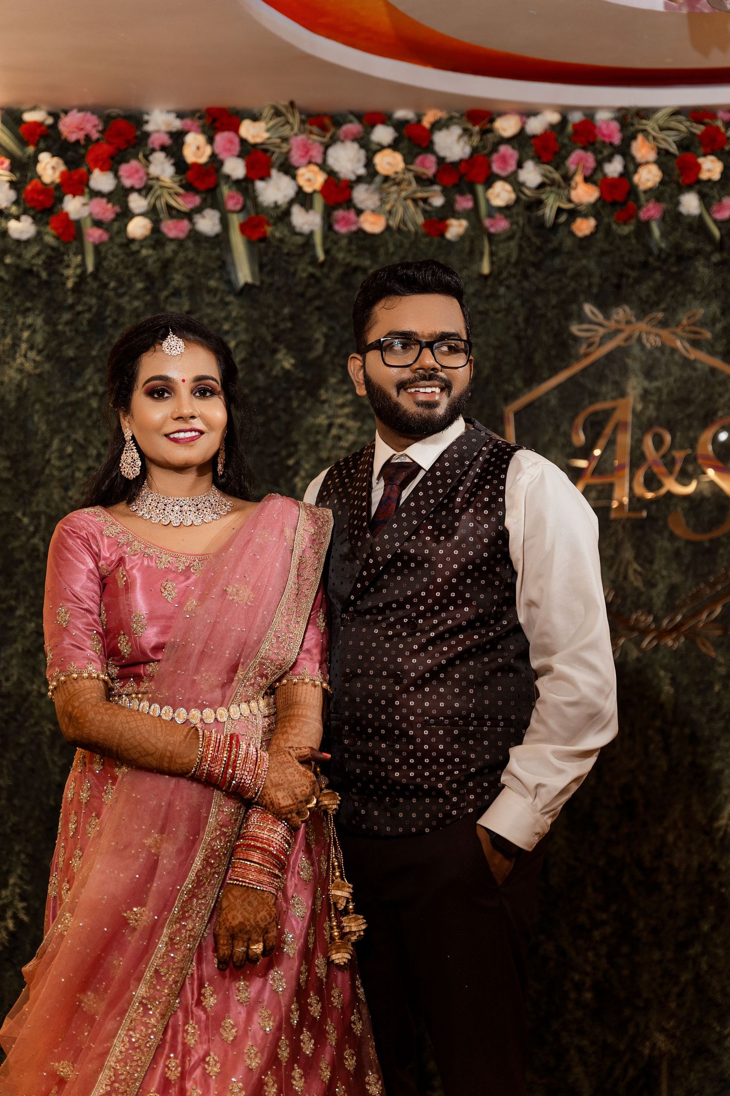 Wedding reception portrait with floral backdrop and elegant traditional Indian attire.