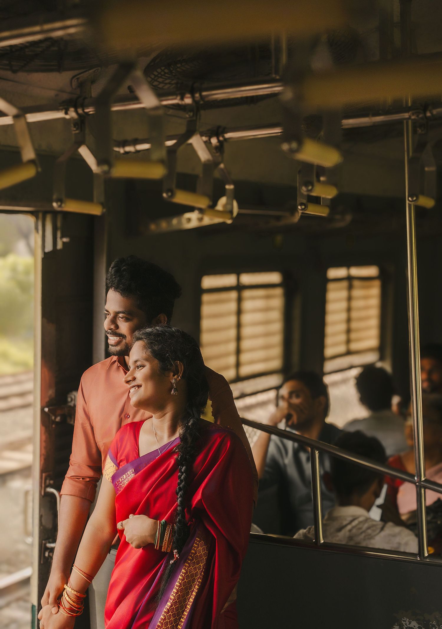 Couple in traditional Indian clothing share tender moment during train journey.