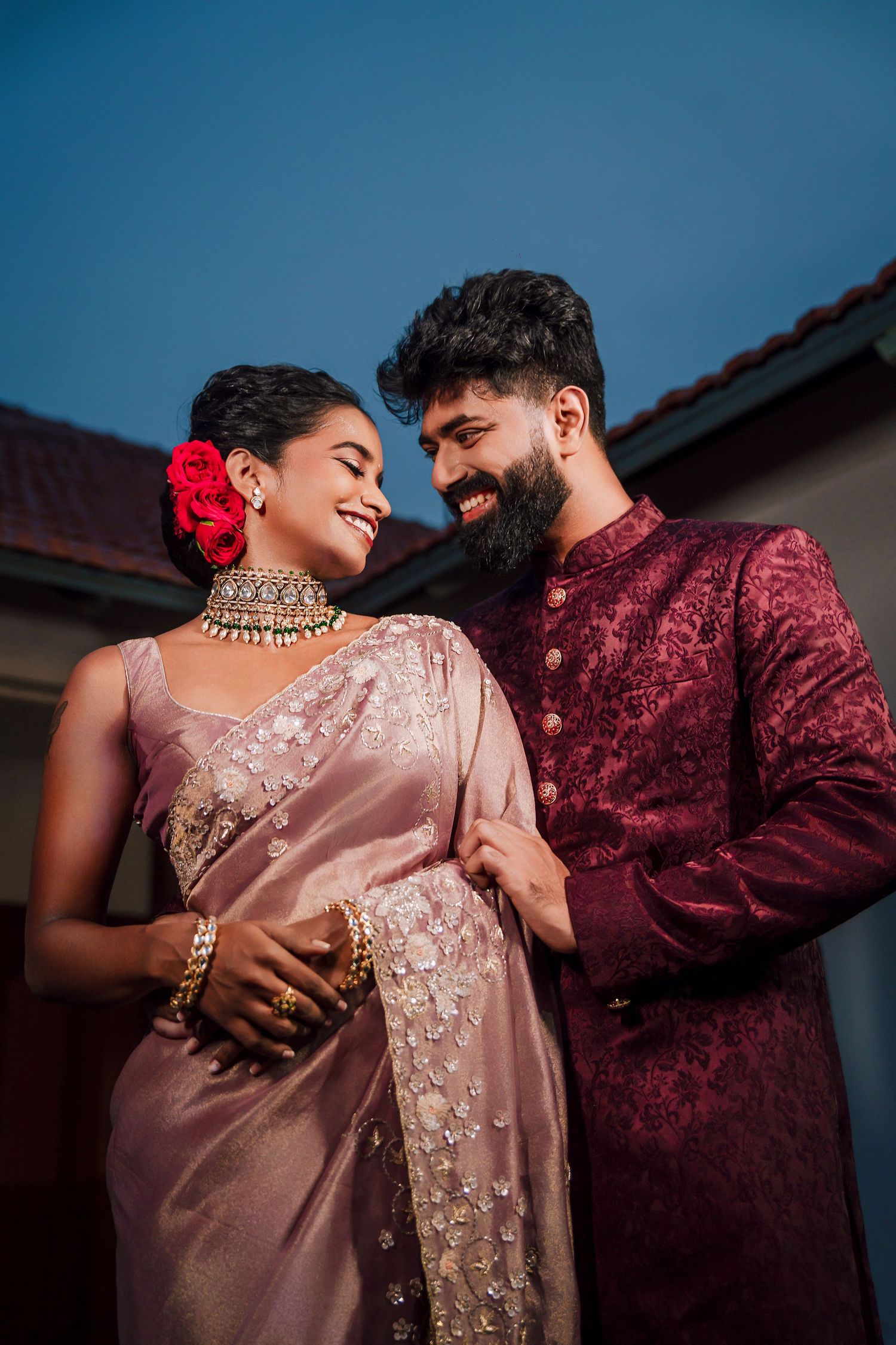 Couple in elegant Indian wedding attire sharing a romantic moment outdoors.