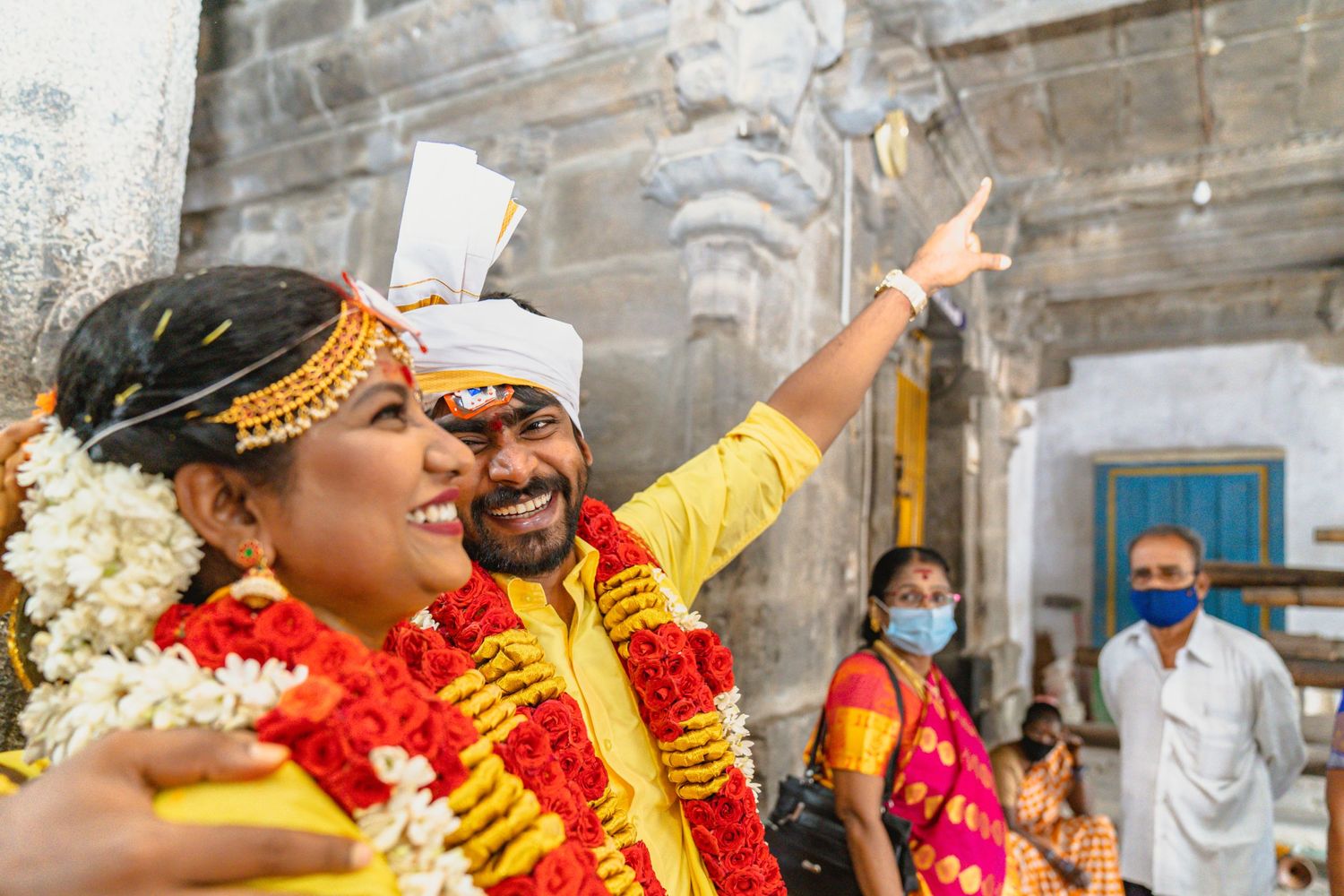 Joyous celebration with participants wearing yellow attire and floral garlands at a traditional event.