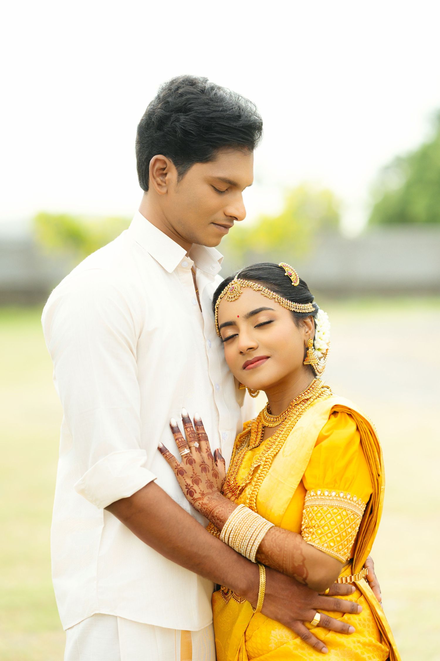 A romantic couple in traditional attire share tender moments during an outdoor photoshoot.
