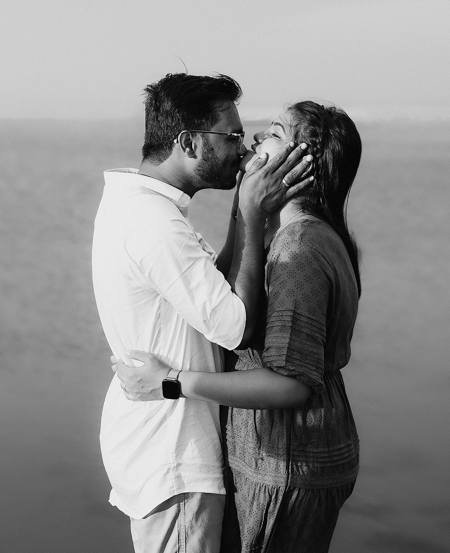 Black and white photograph capturing a romantic interaction between two people outdoors.