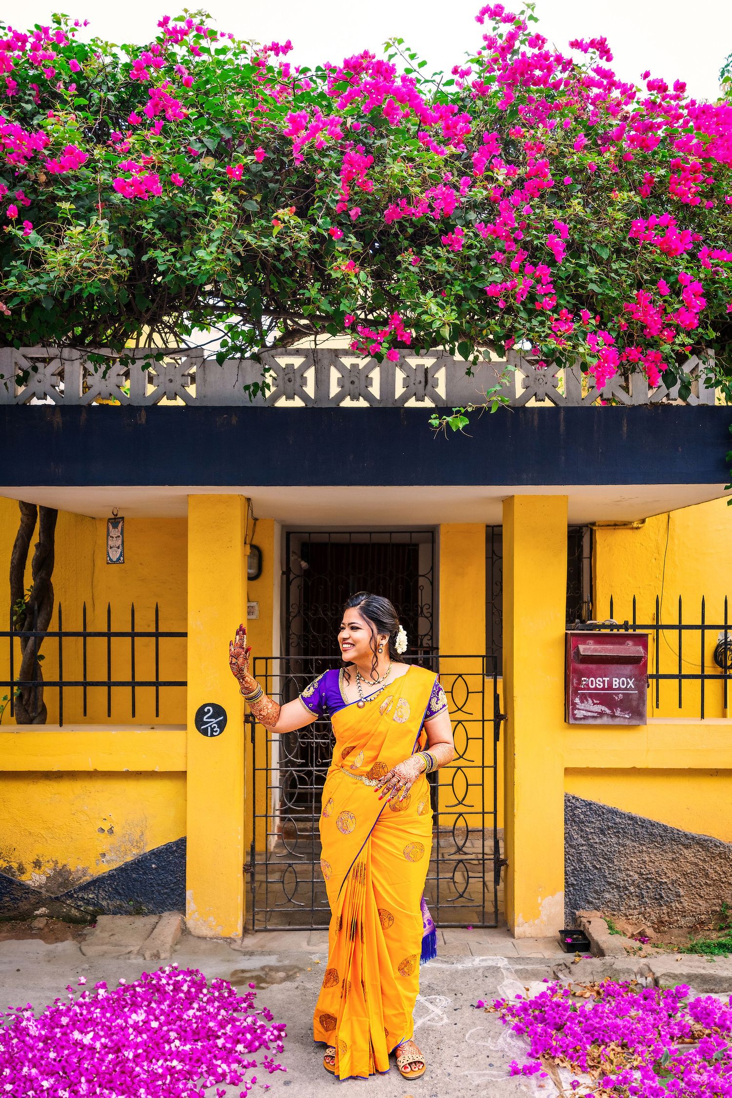 Yellow architectural facade with ornate ironwork and blooming pink bougainvillea flowers.