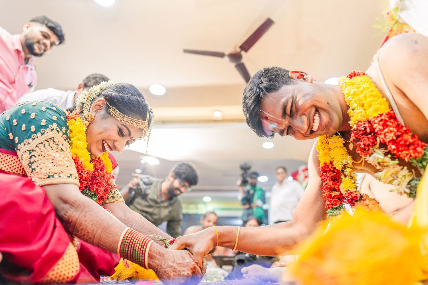 Traditional Indian wedding ritual showing participants laughing while performing ceremonial customs.
