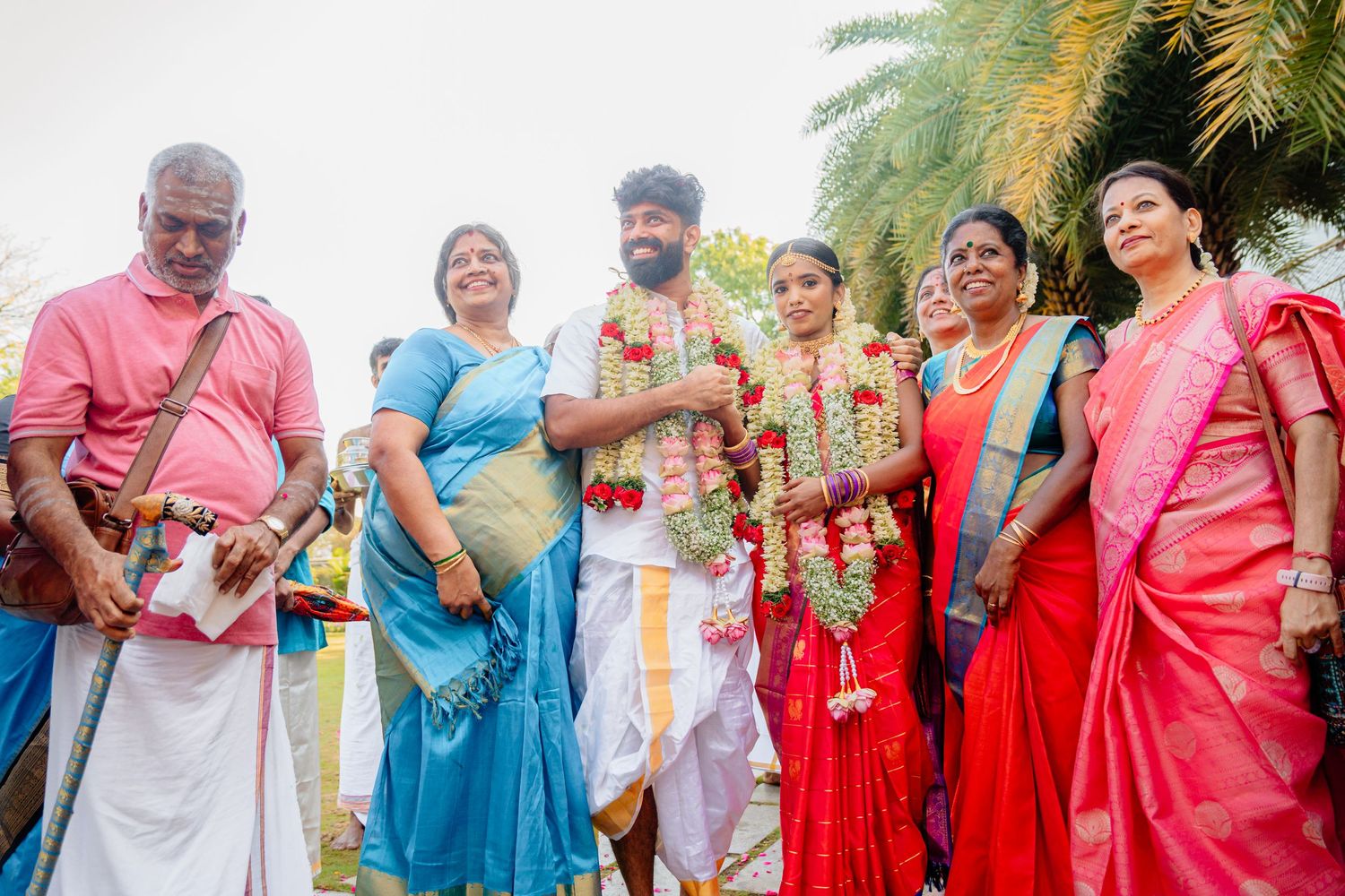 Group wearing vibrant traditional South Indian attire poses together at an outdoor celebration.