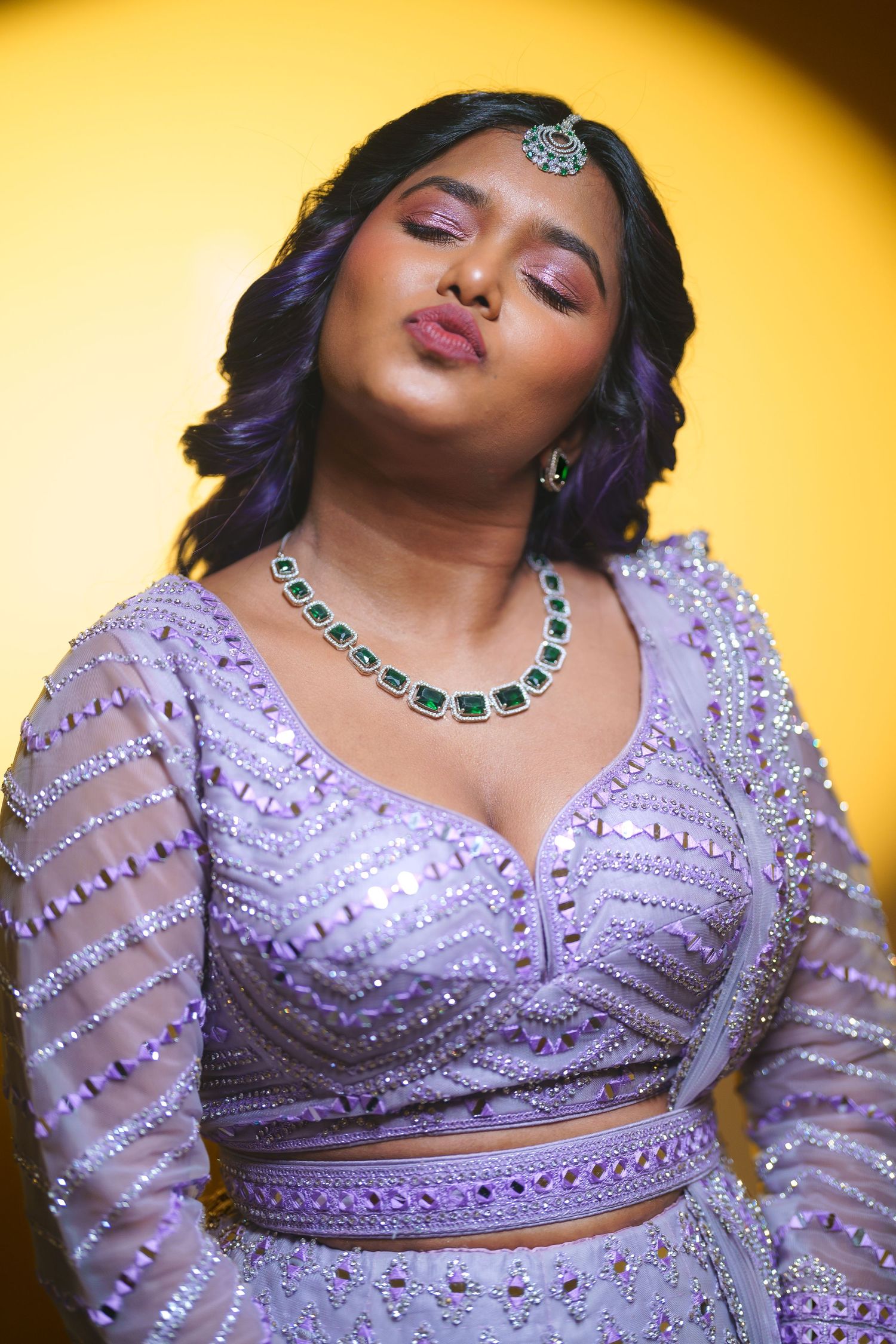 Fashion portrait against yellow background featuring purple dress and statement necklace.