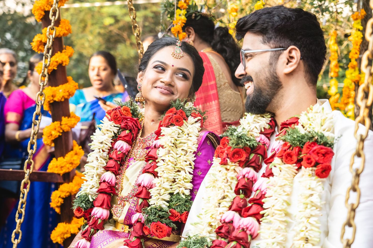 Traditional Hindu wedding ceremony with couple wearing flower garlands and bright attire.