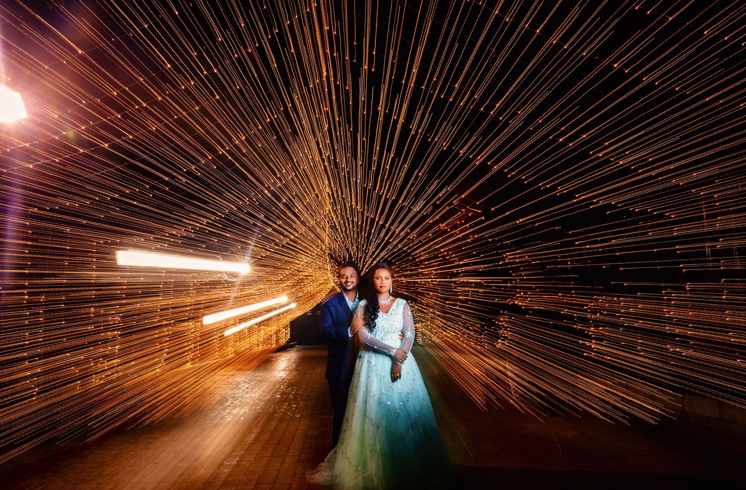 Artistic wedding photograph captures streaming light rays surrounding a couple in formal attire.
