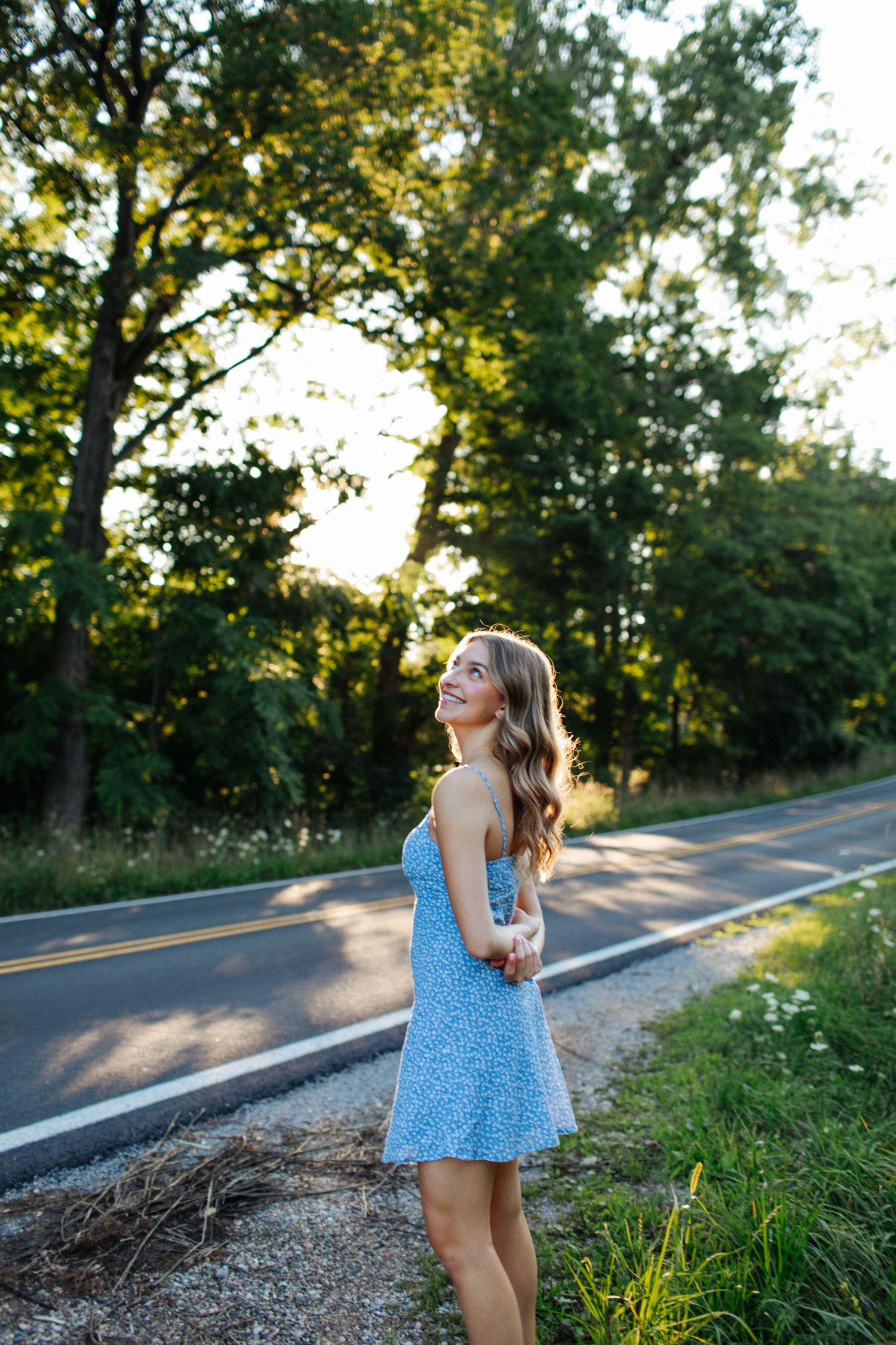 A sequence of playful outdoor portraits in a blue dress along a country road at sunset.