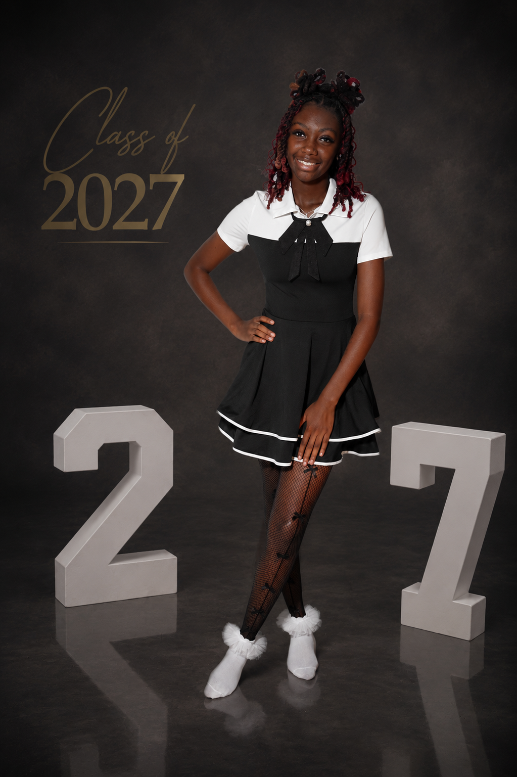 A smiling student poses in a black and white dress for a Class of 2027 senior portrait photo session.