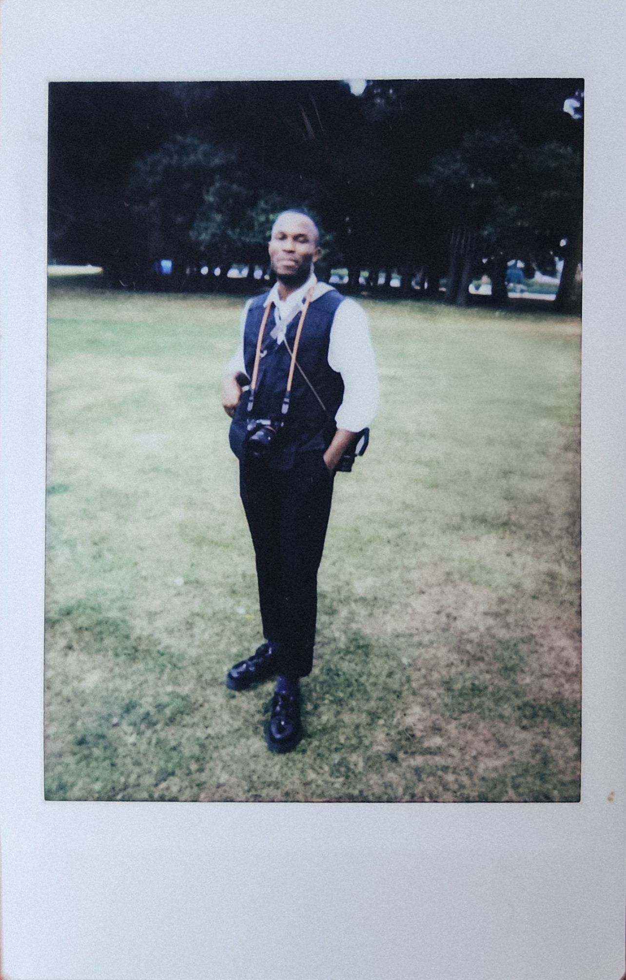 Polaroid photo of the photographer with a medium format camera hanging from a camera strap around his neck