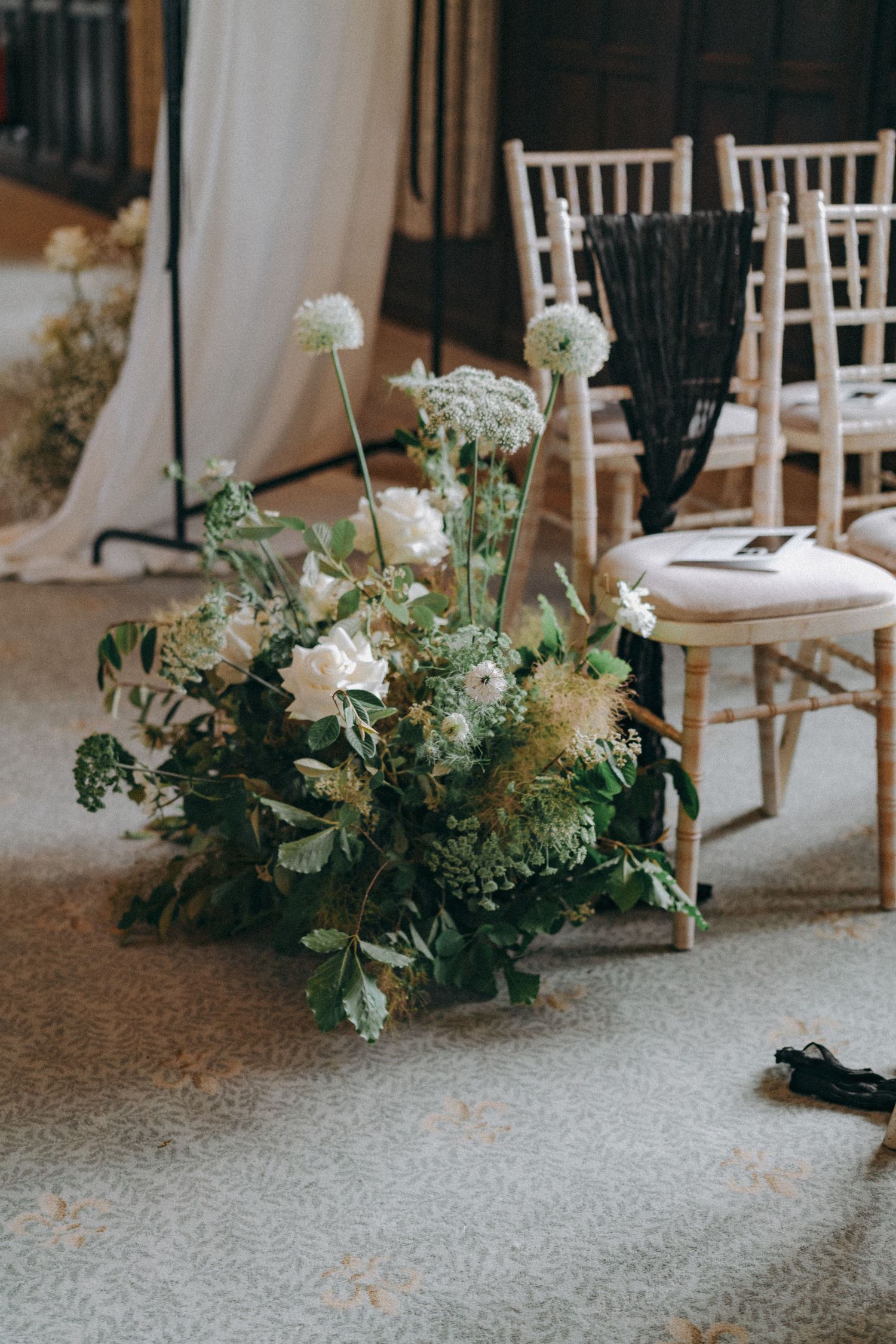 Floral arrangement at the foot of a chair in a wedding ceremony venue