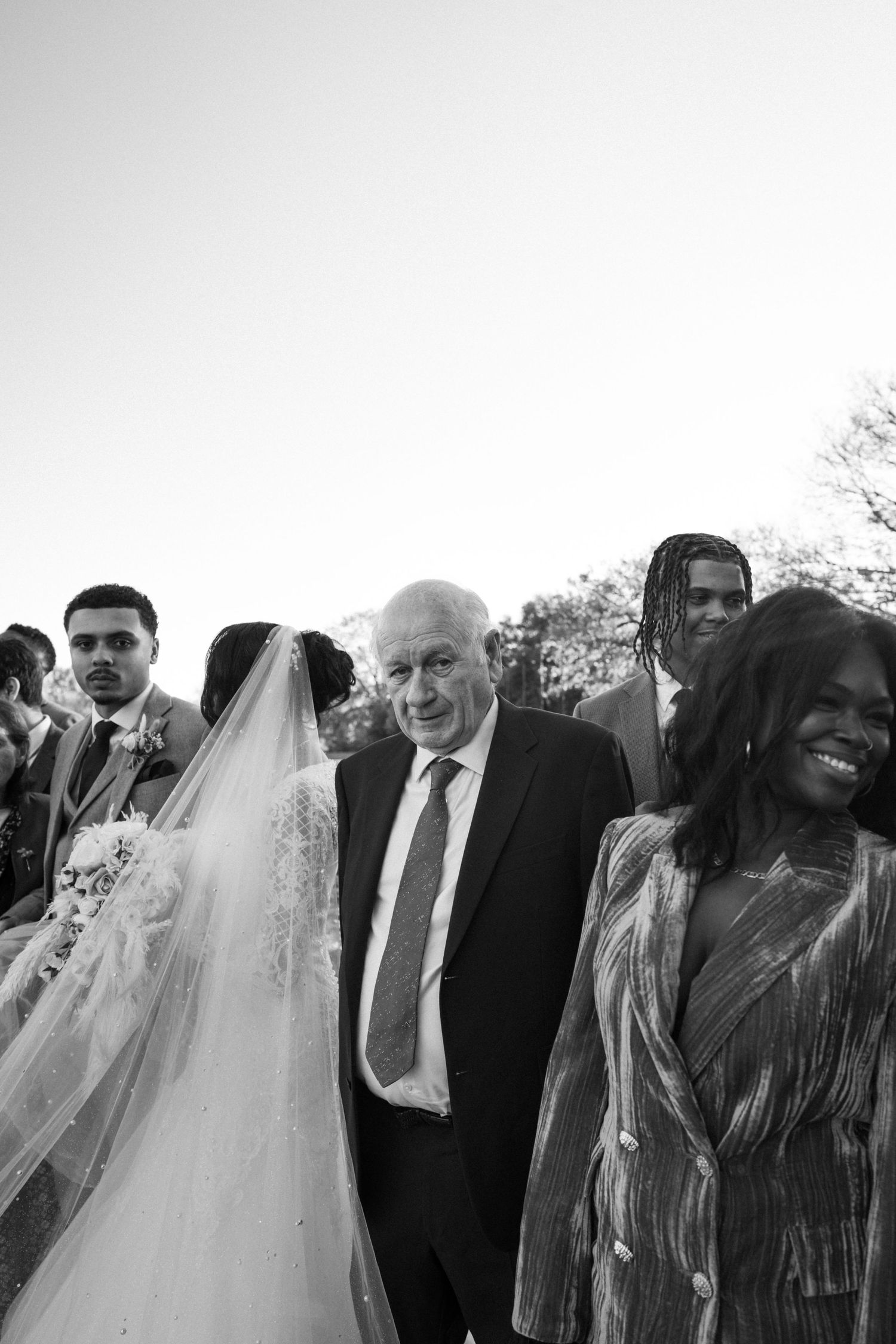 intergenerational wedding moment. Group laughing with Bride & groom whilst elderly man looks at camera