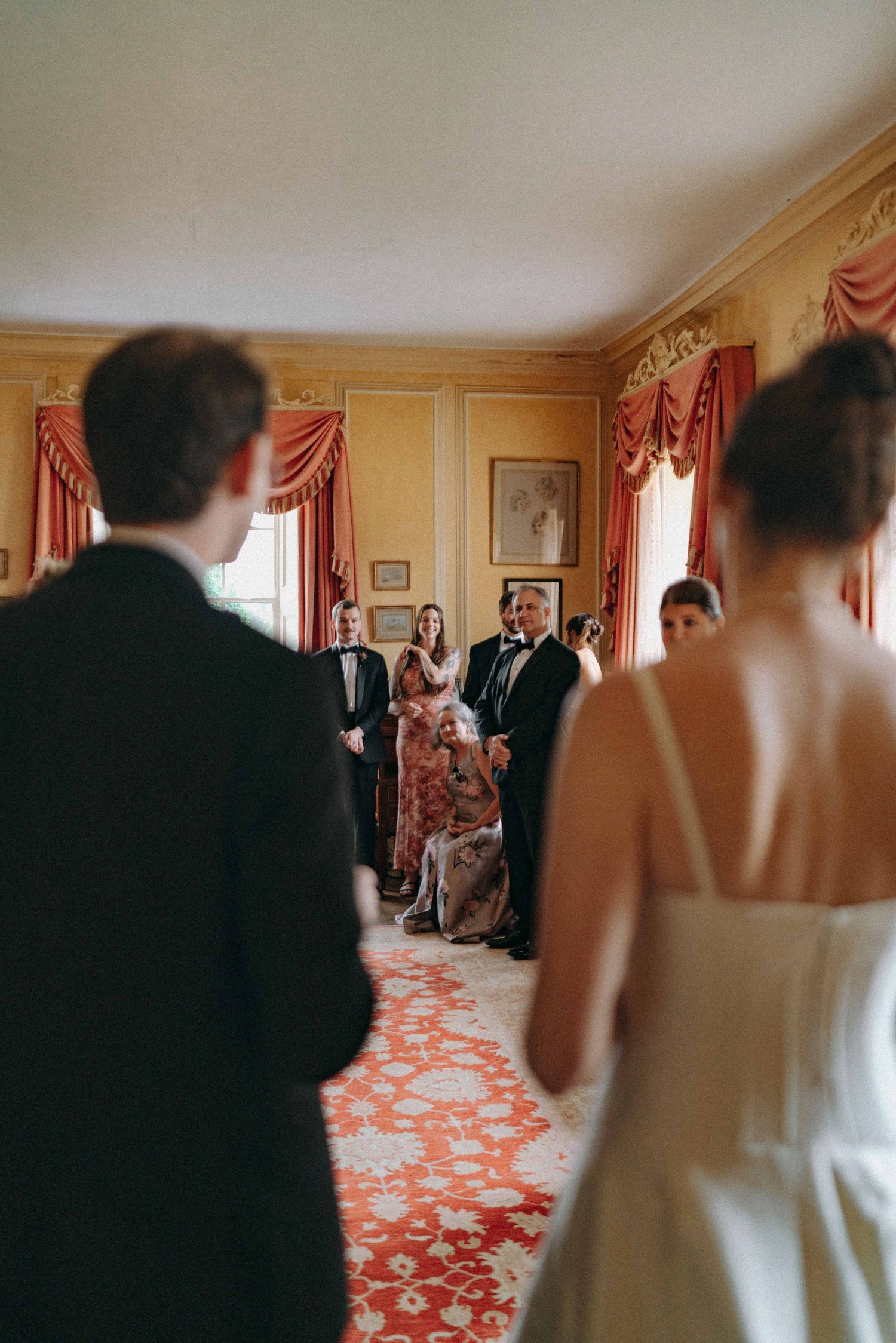 3rd person view Candid moment as bride & groom enter a room with family. Documentary wedding